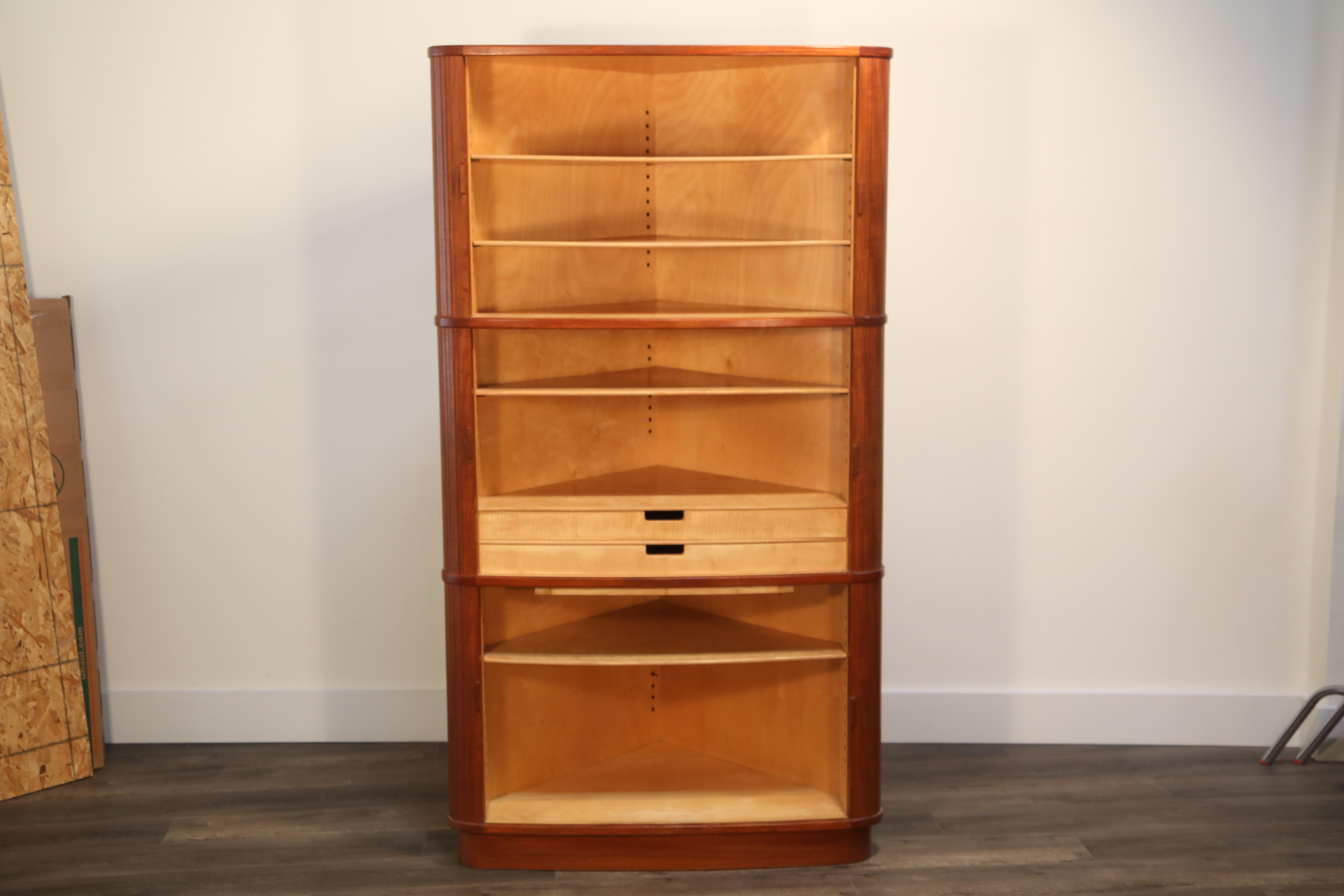 This incredibly useful Mid-Century Modern corner cabinet constructed in teak exterior and beech wood interiors features tambour doors, two drawers and a slide out table. So many homes have an empty corner, in desperate need of a corner cabinet -