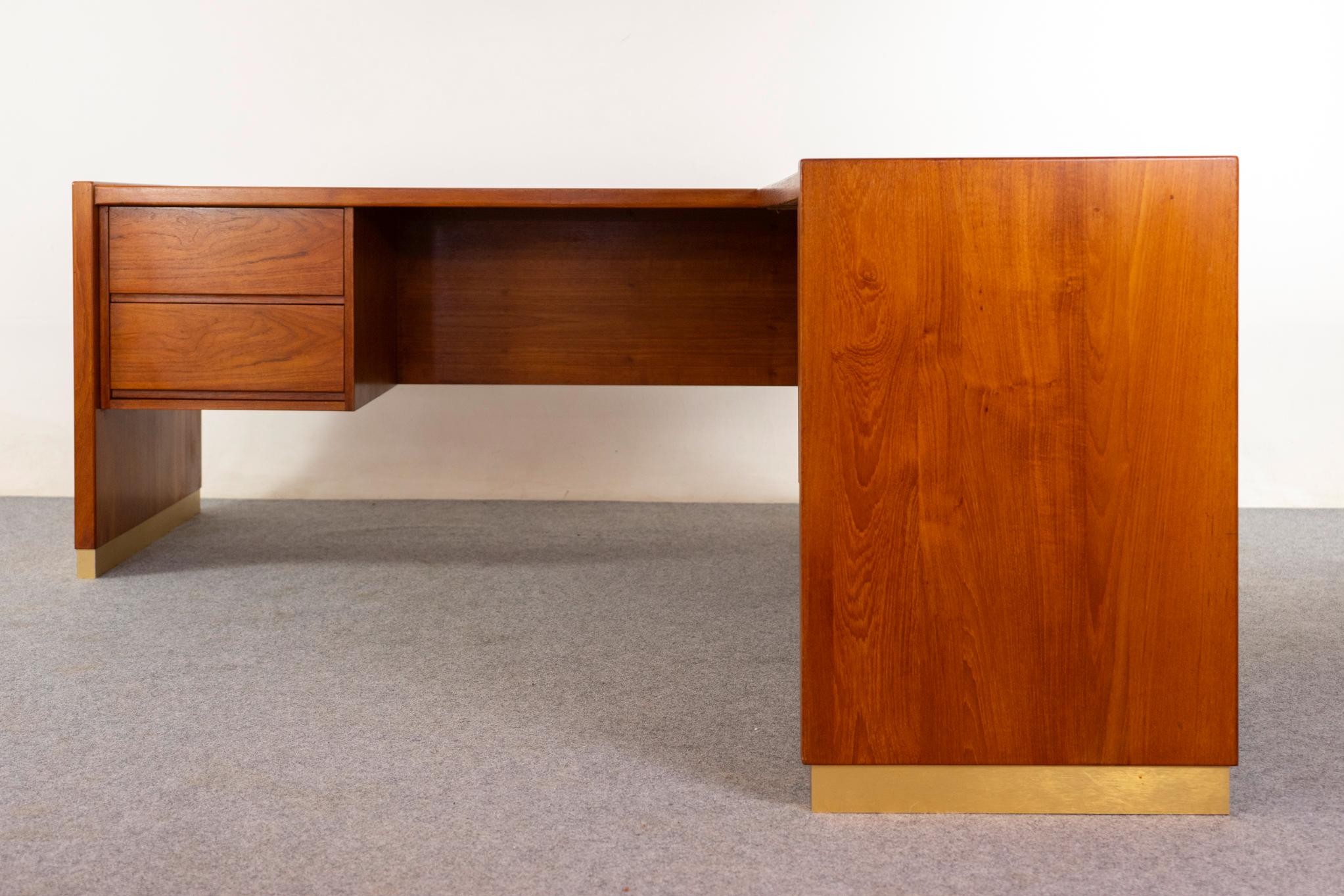 Teak corner desk, circa 1960s. Impressive book matched veneer top with robust solid sides with contrasting brass trim.

Please inquire.