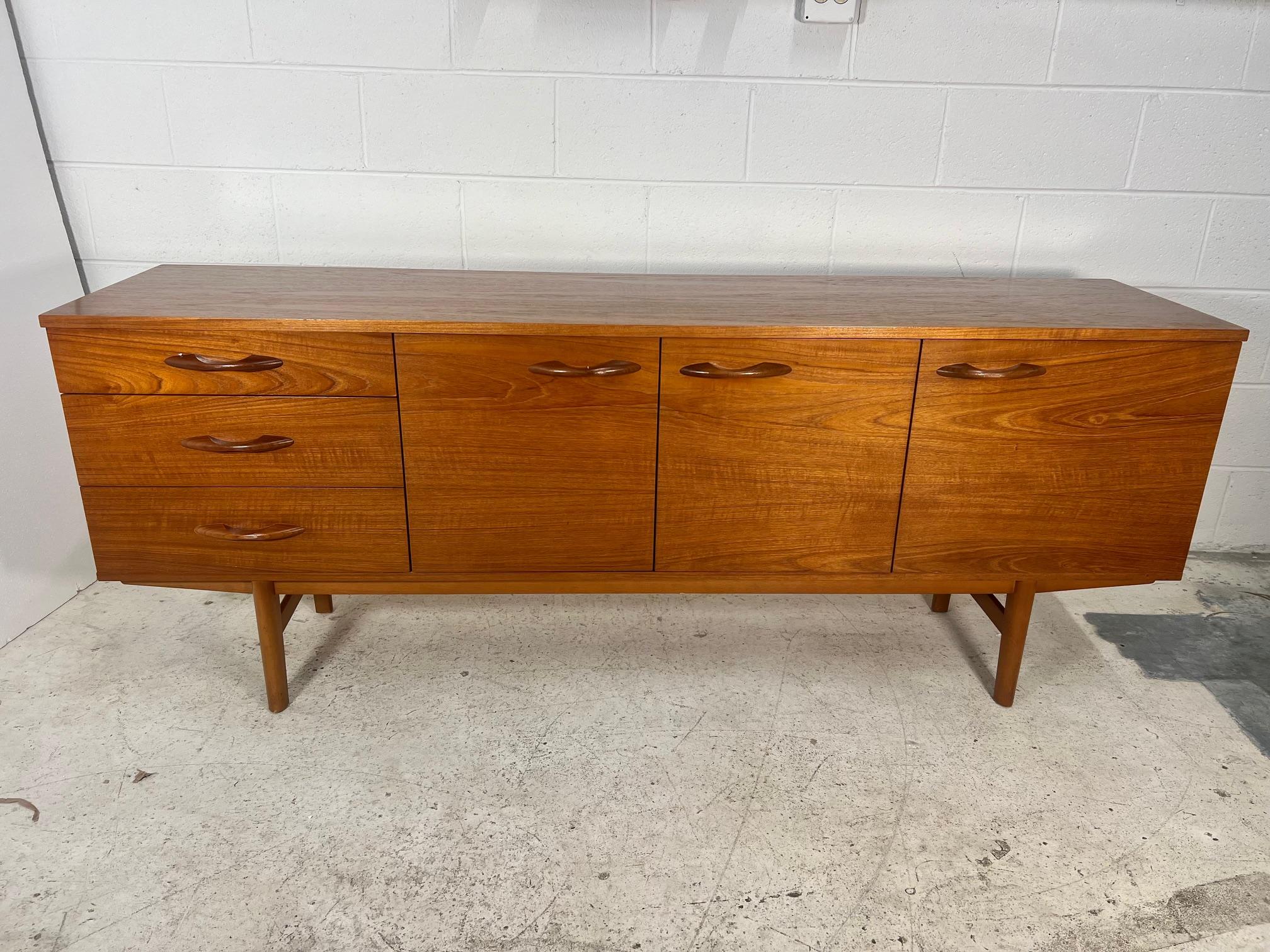 Teak credenza by Avalon. Made in England.

Three drawers on the right side. Beautiful large sculpted teak handles.

Excellent condition. Small chip in one corner as shown in photos.
Dimensions: 72