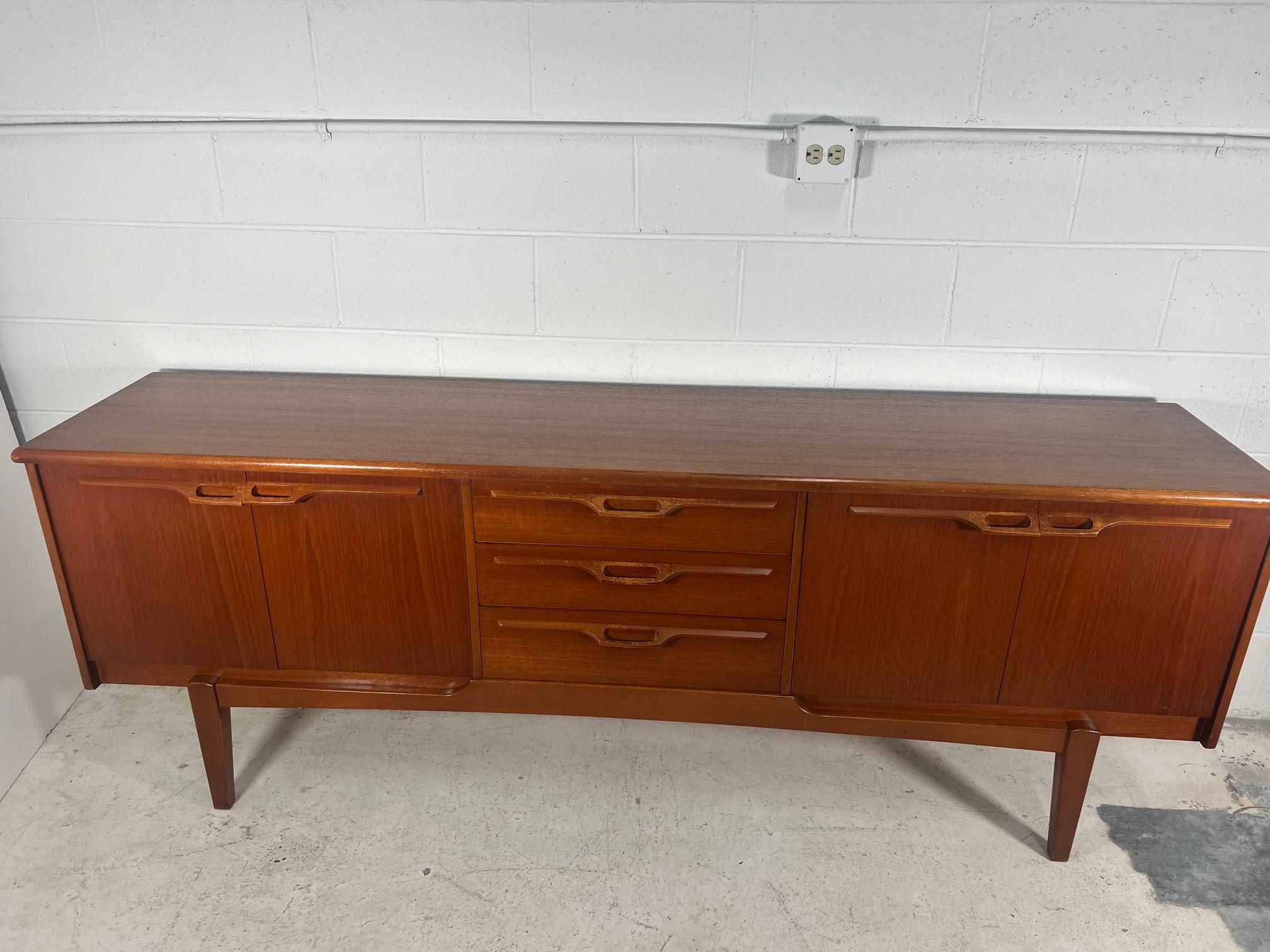 This stunning mid-century modern teak credenza by Jentique is a must-have for any stylish home. The rich brown color and sleek design make it a perfect addition to any room. With two shelves and ample space, it provides both style and functionality.