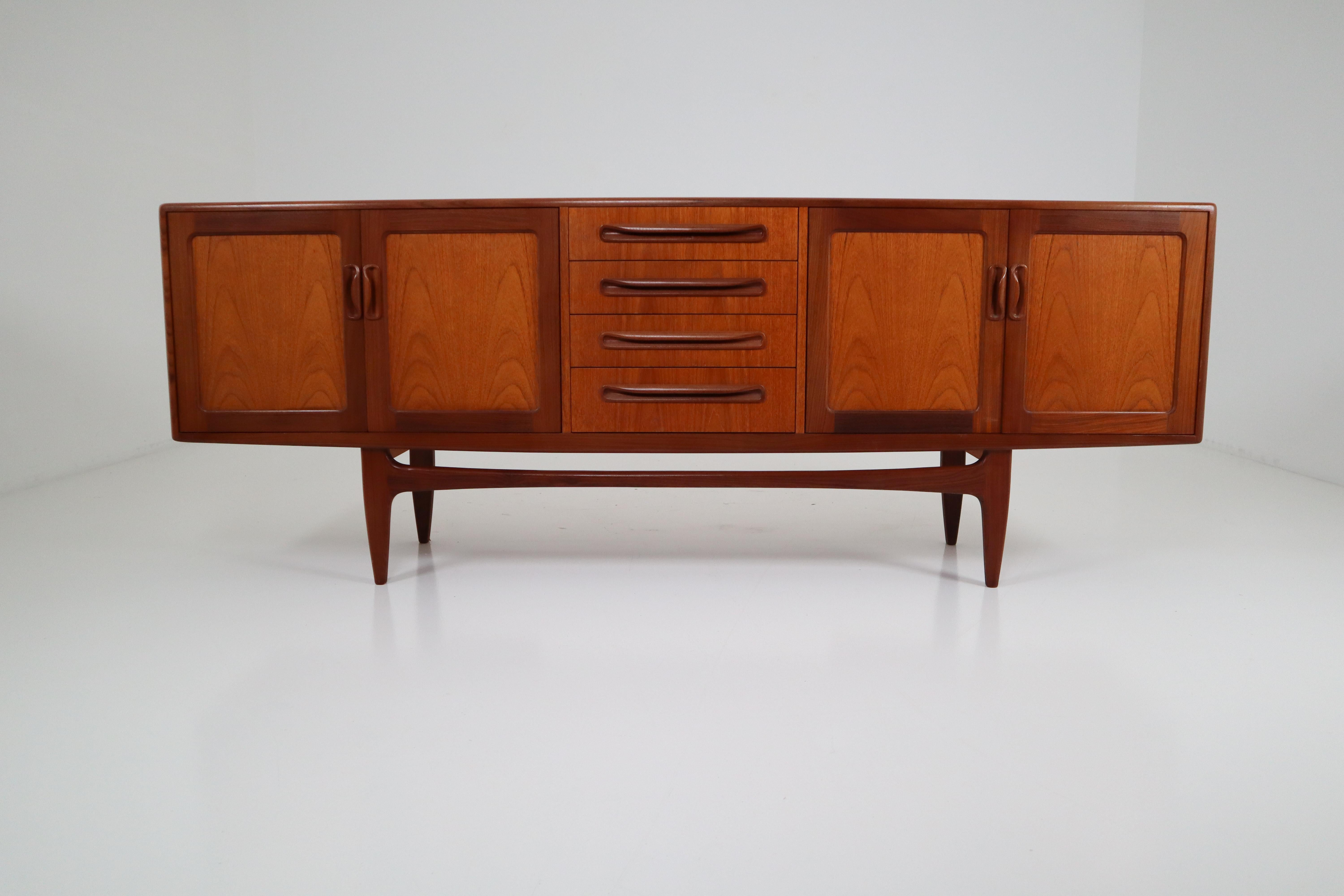 Mid-Century Modern credenza teak wood construction, dovetail drawers. Featuring 4 drawers centre with top silverware drawer, 4 doors with shelf and amazing sculptural hand pulls. Beautiful bookmatched figured wood. The sideboard has a nice patina