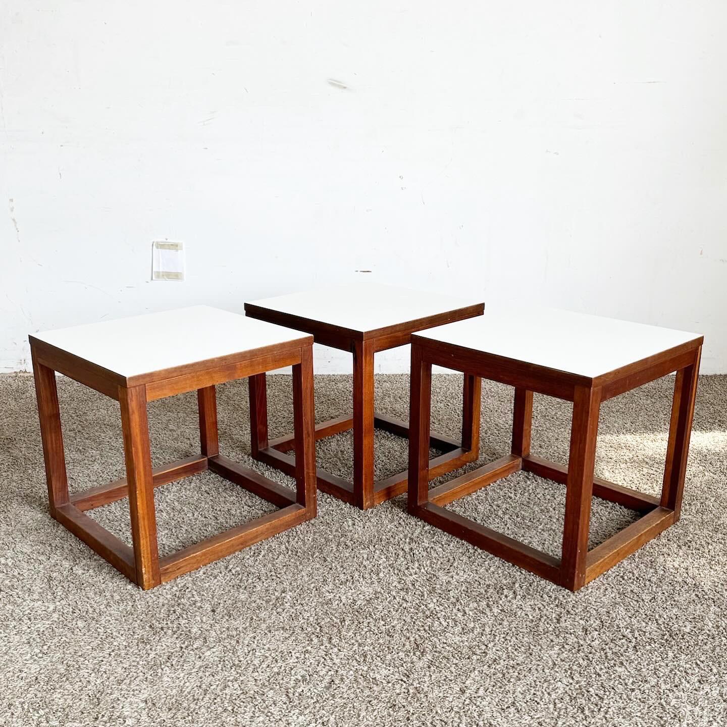 Die Mid Century Modern Teak Cubic Side Tables - 3er-Set fangen die Essenz des Mid-Century-Designs ein. Die Tische aus langlebigem Teakholz mit schöner Maserung zeichnen sich durch klare geometrische Linien und eine minimalistische kubische Form aus.