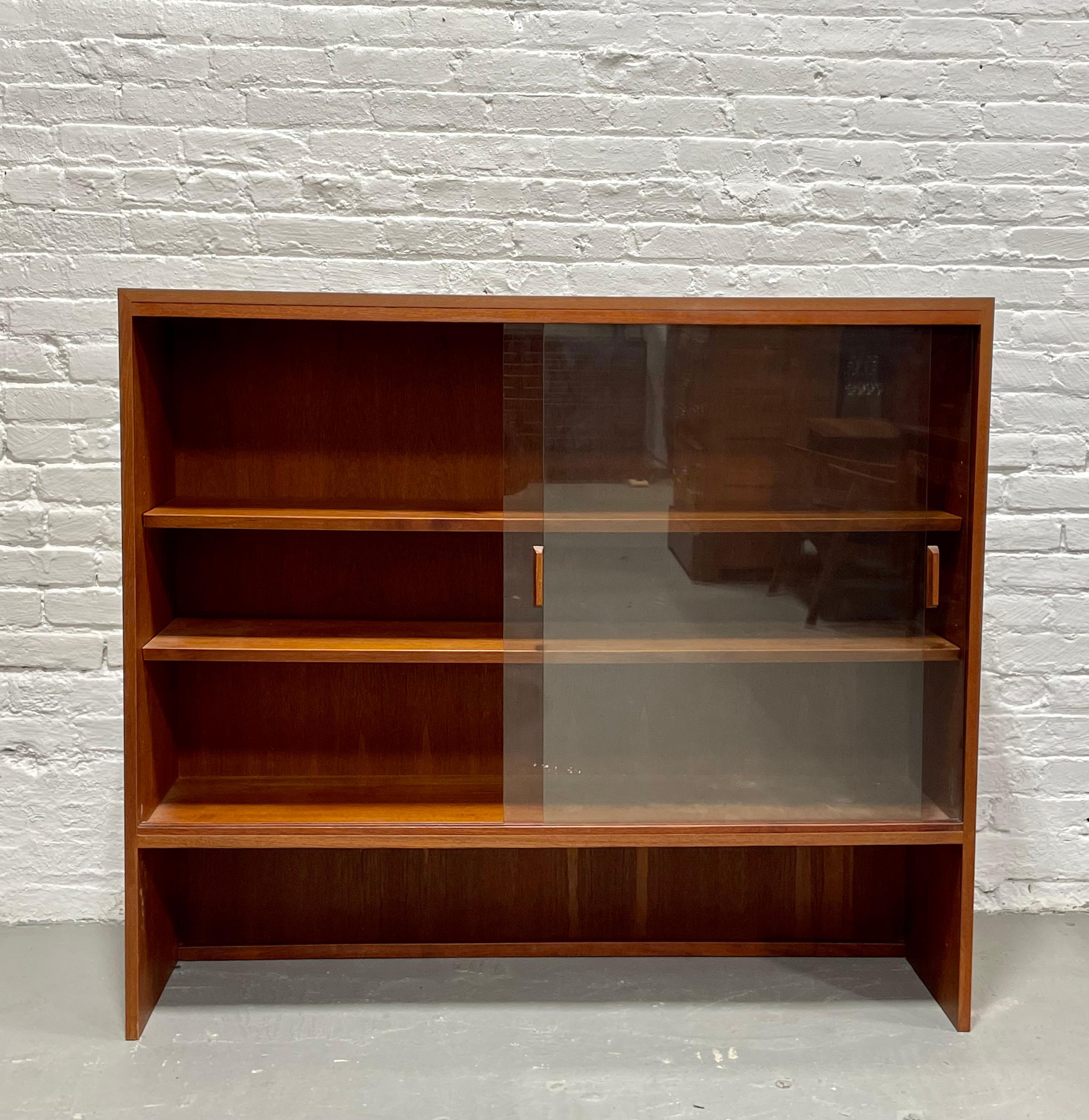 Mid-Century Modern Teak Danish bookcase / hutch, circa 1960s. Plenty of room for books or displaying your collection. This narrow piece makes it a great choice for a hallway or long wall space. The glass doors keep the dust out and there is a lovely