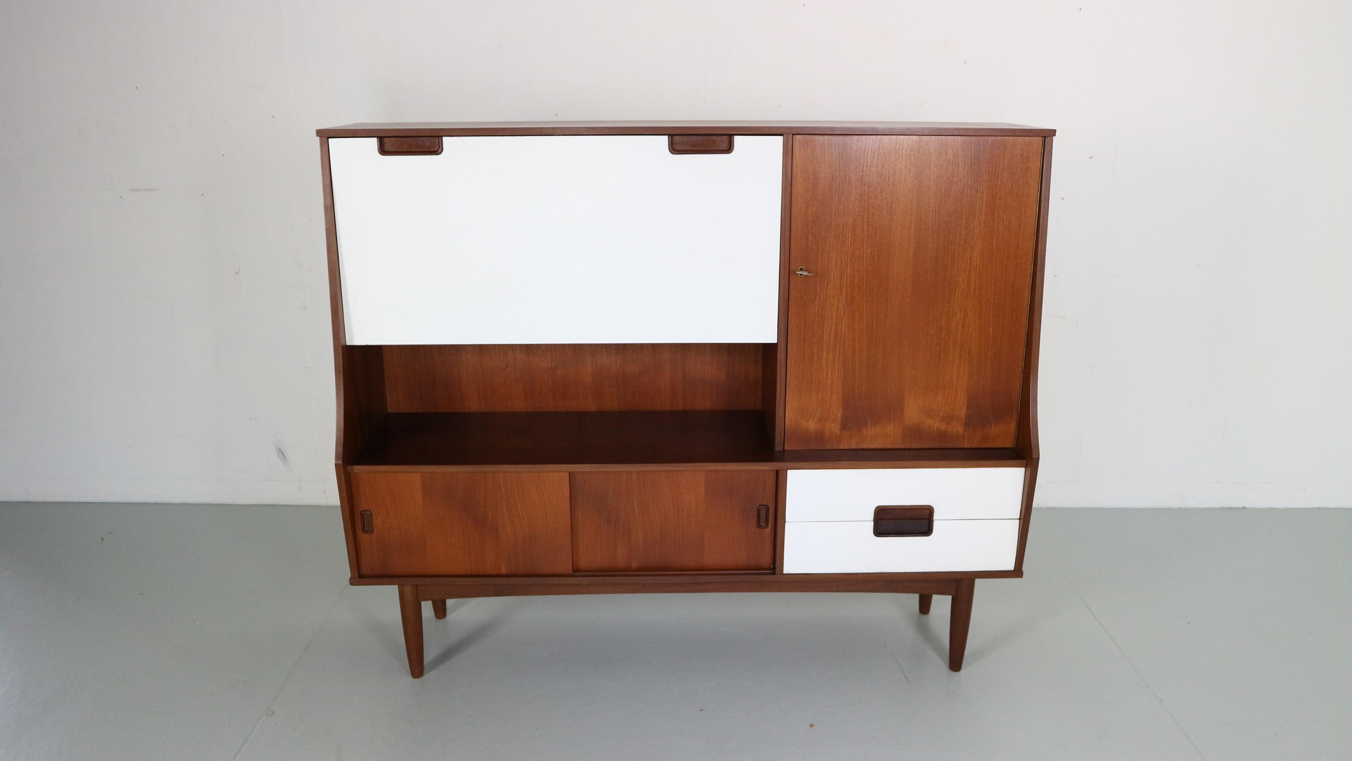 Mid- Century modern period buffet cabinet but also can be easily used as a secretary made in 1960's period, Denmark.

Teak cabinet with white formica details on the cabinets.
One working lock with the key.
Plenty of storage spaces from shelves to