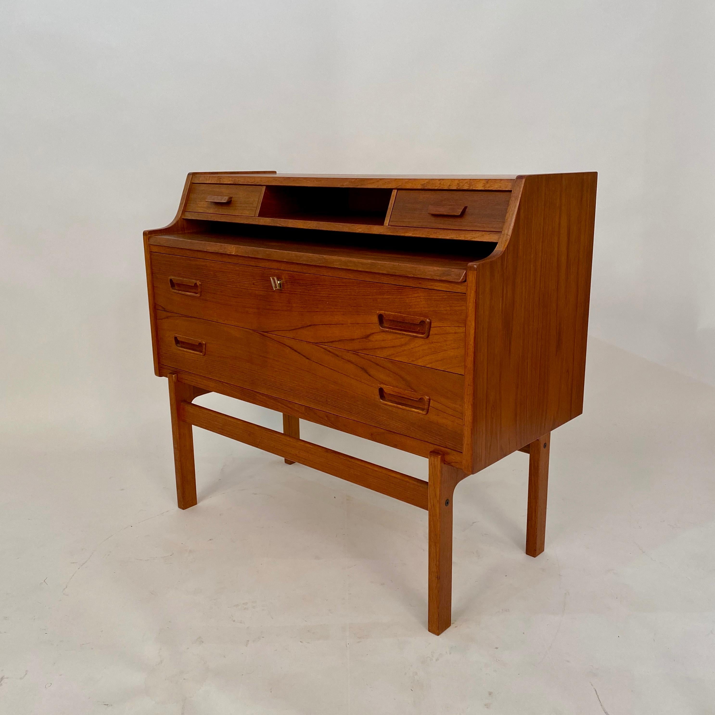 This beautiful teak secretary desk was designed by Arne Wahl Iversen and made in Denmark by Vinde Møbelfabrik.
This desk has two large drawers, including one that locks, two small drawers, a cubbyhole, and a retractable writing surface.
The depth