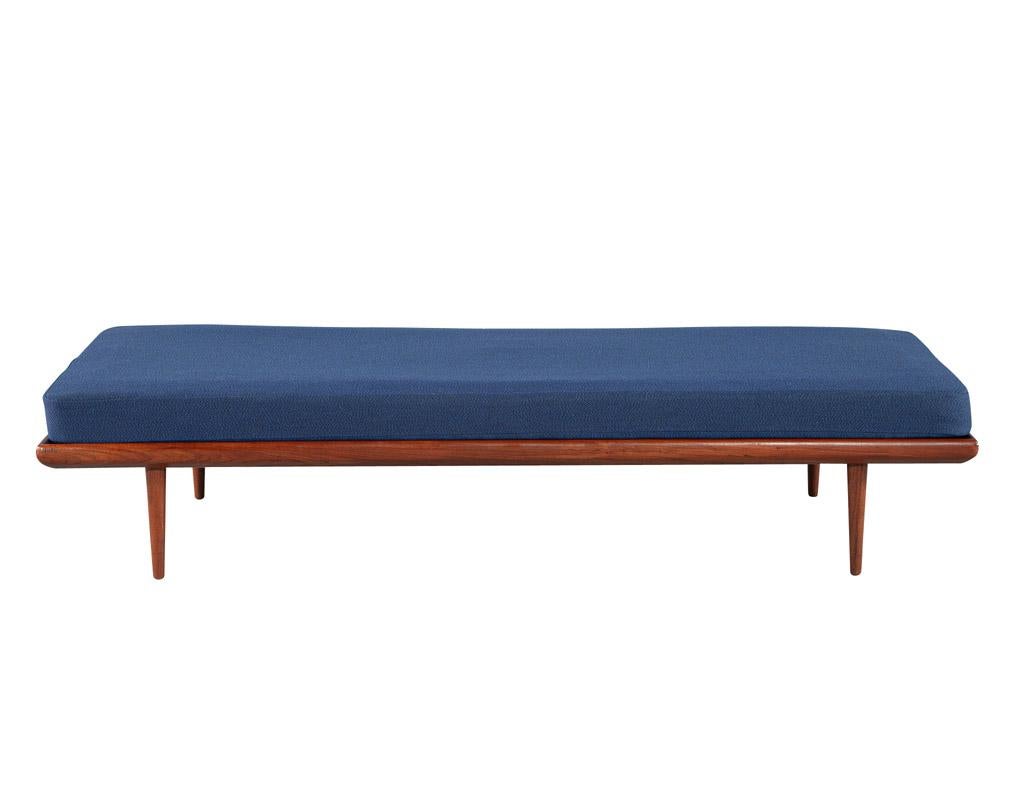 This beautiful vintage mid-century modern daybed, made in Denmark circa 1970's, is a timeless piece of craftsmanship and design. The frame is made from teak wood, giving it a warm and classic feel. The large seat cushion is upholstered in a navy