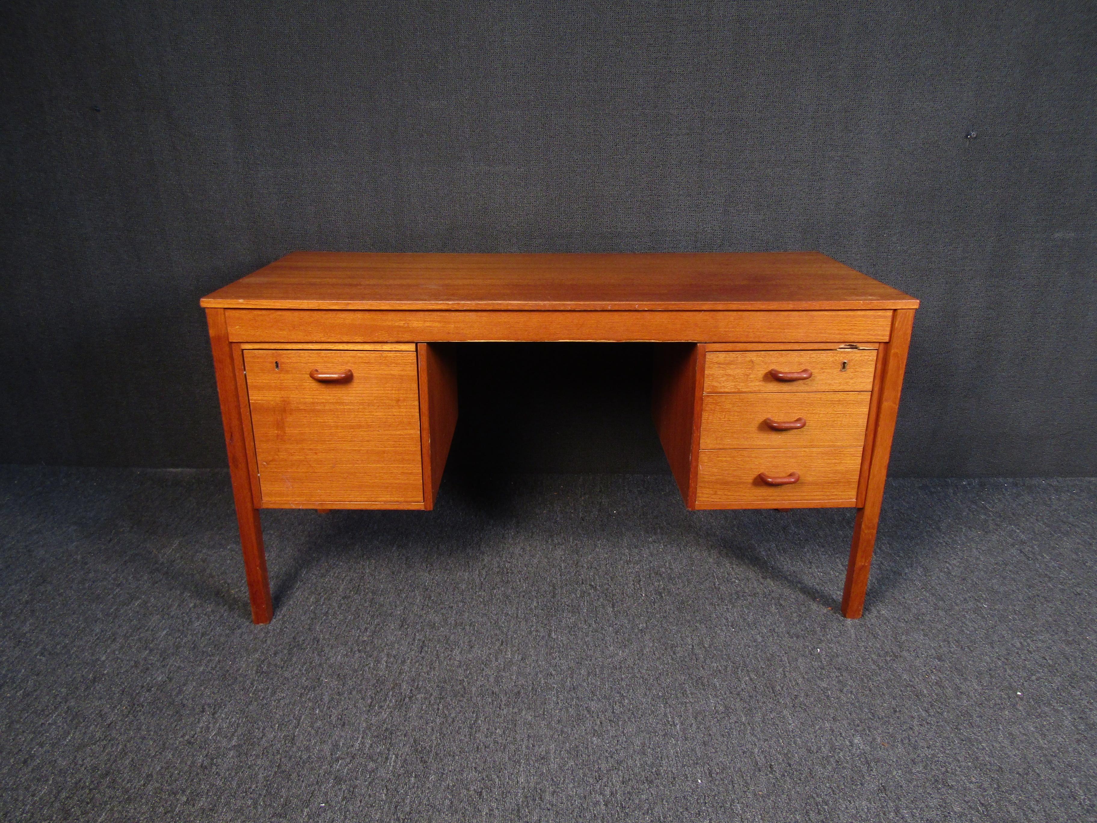 Teak desk with four drawers. Solid piece with original finish.