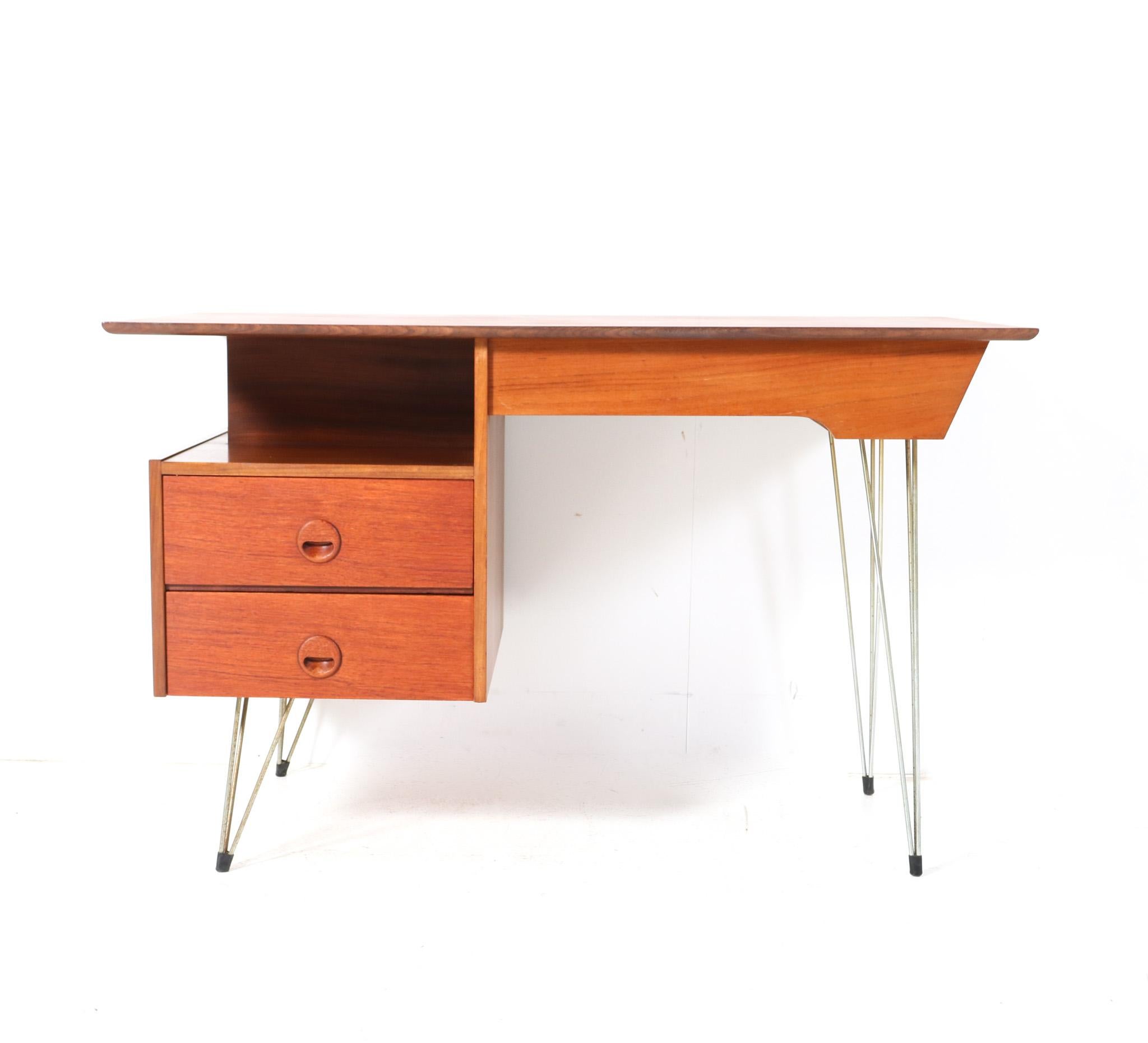 Stunning and elegant Mid-Century Modern desk or writing table.
Design by Louis Van Teeffelen for WéBé.
Striking Dutch design from the 1950s.
Minimalistic design in solid teak and original teak veneer with original lacquered metal hairpin legs.
Two