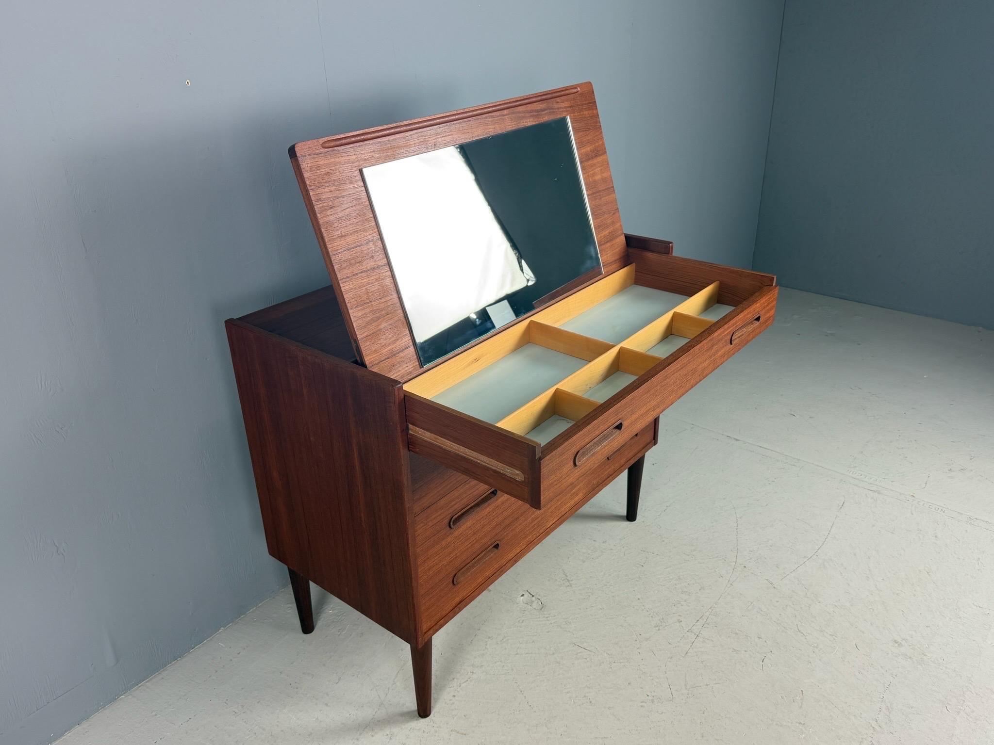 Table de toilette ou de maquillage d'époque Mid-Century Modern, également utilisable comme bureau, fabriquée au Danemark en 1960. 
Bois plaqué teck avec poignées et pieds en teck massif.
 Quatre tiroirs et un miroir lorsque vous ouvrez la partie