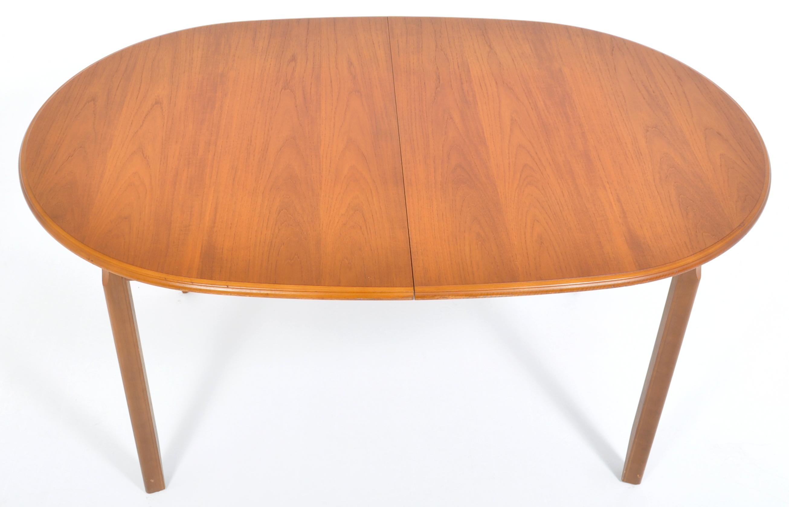 Mid-Century Modern teak dining table by Meredew, 1960s. The table having two sliding demi-lune ends enclosing a single fold-out butterfly leaf. The table having gently chamfered legs, manufacturer's label to the underside of the leaf.

Measures: