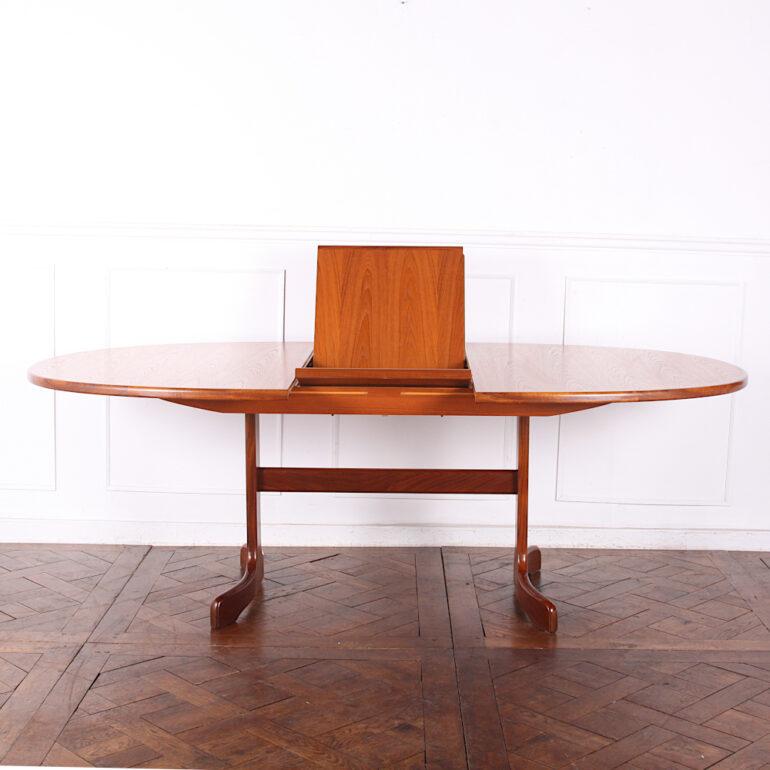 Stylish Mid-Century Modern teak oval dining table with a folding ‘butterfly’ leaf stored beneath the top, the base with a pair of ‘whale tail’ pedestal supports united by a stretcher. 

.
