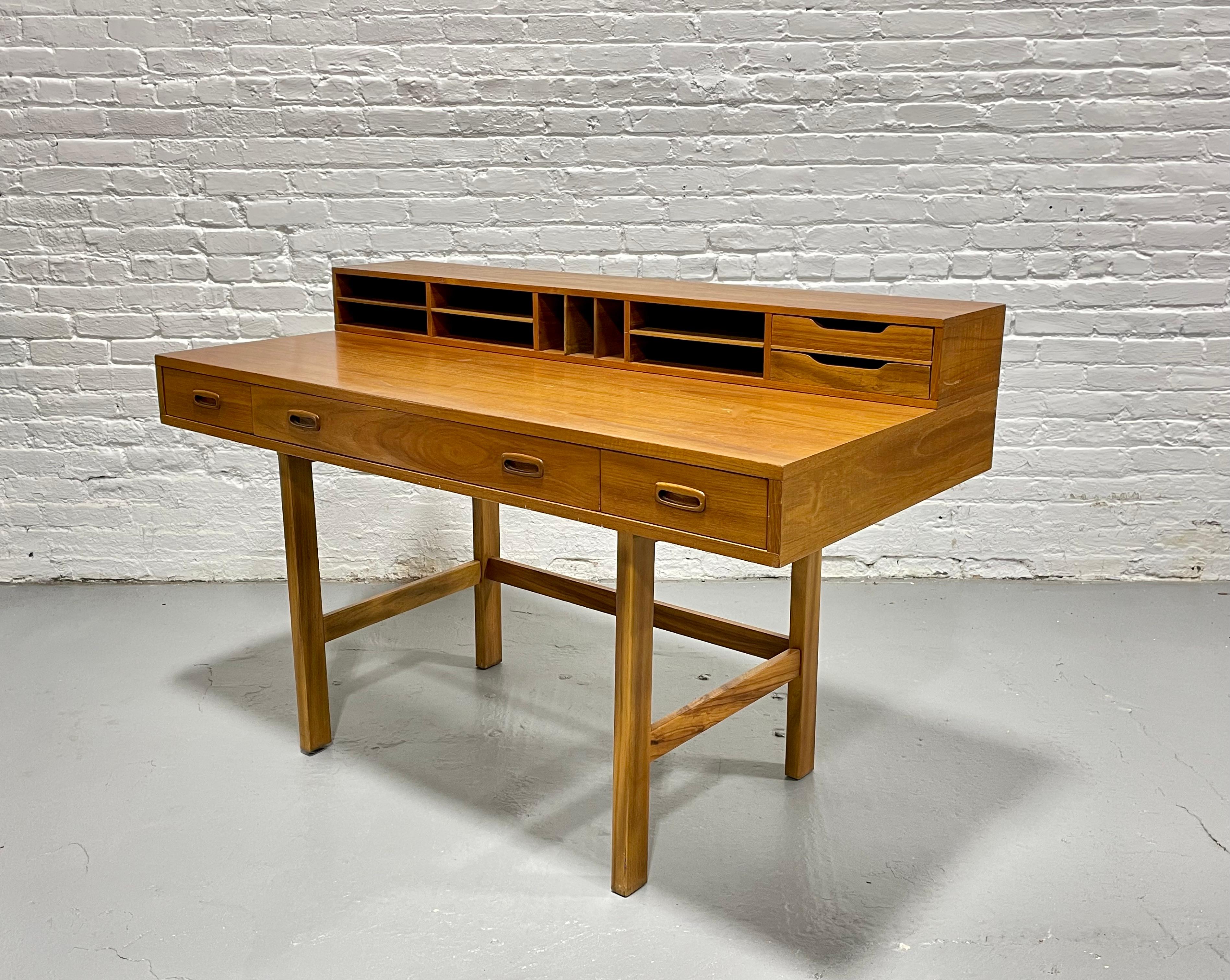 Mid Century Modern Teak Desk by Scova for Dixie, in the style of Peter Lovig, circa 1960s. This beauty offers three drawers along the front and plenty of cubbies for all your office supplies. Best of all, the cubby area flips back to allow for a
