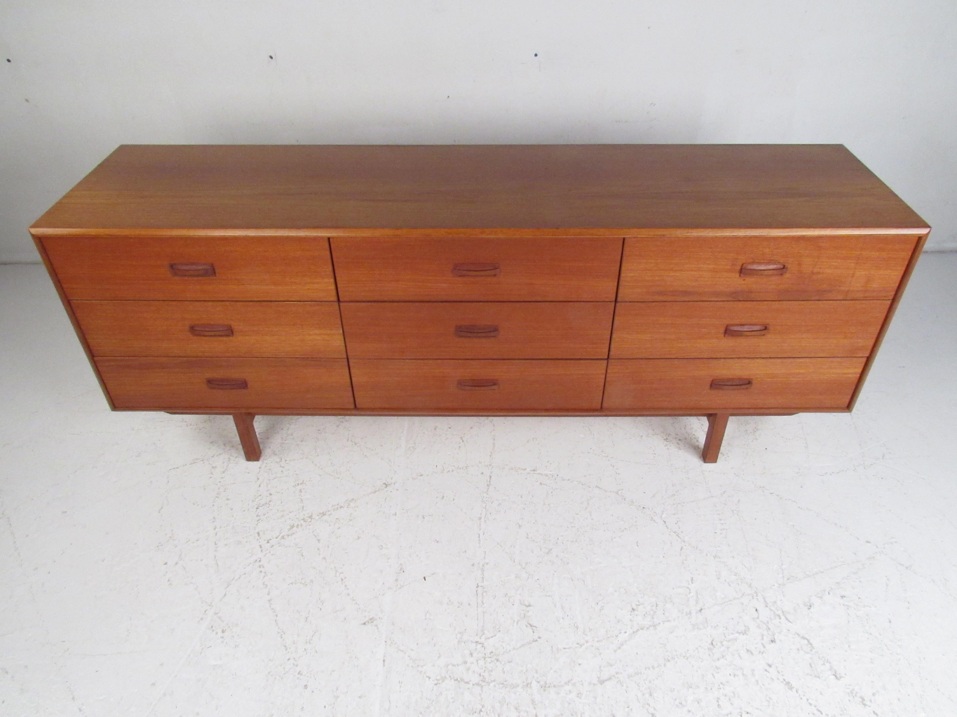 This stunning Danish modern dresser features nine hefty drawers ensuring plenty of room for storage. The clean lines, rich teak finish, and carved drawer pulls show quality craftsmanship. This sleek midcentury dresser makes the perfect addition to