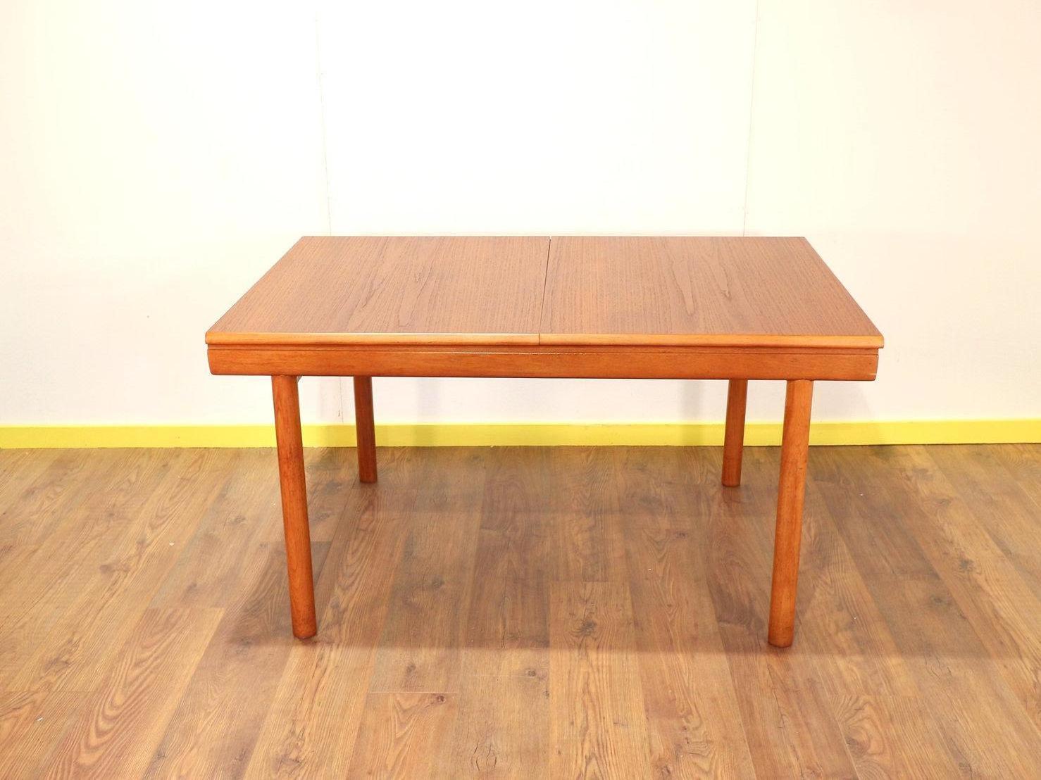 A beautiful large extending teak table by White and Newton with inbuilt extension. Solid teak legs and veneered top with large folding inner leaf and a lovely warm teak colour makes it a very useful table that could sit 6 to 8 people when extended.