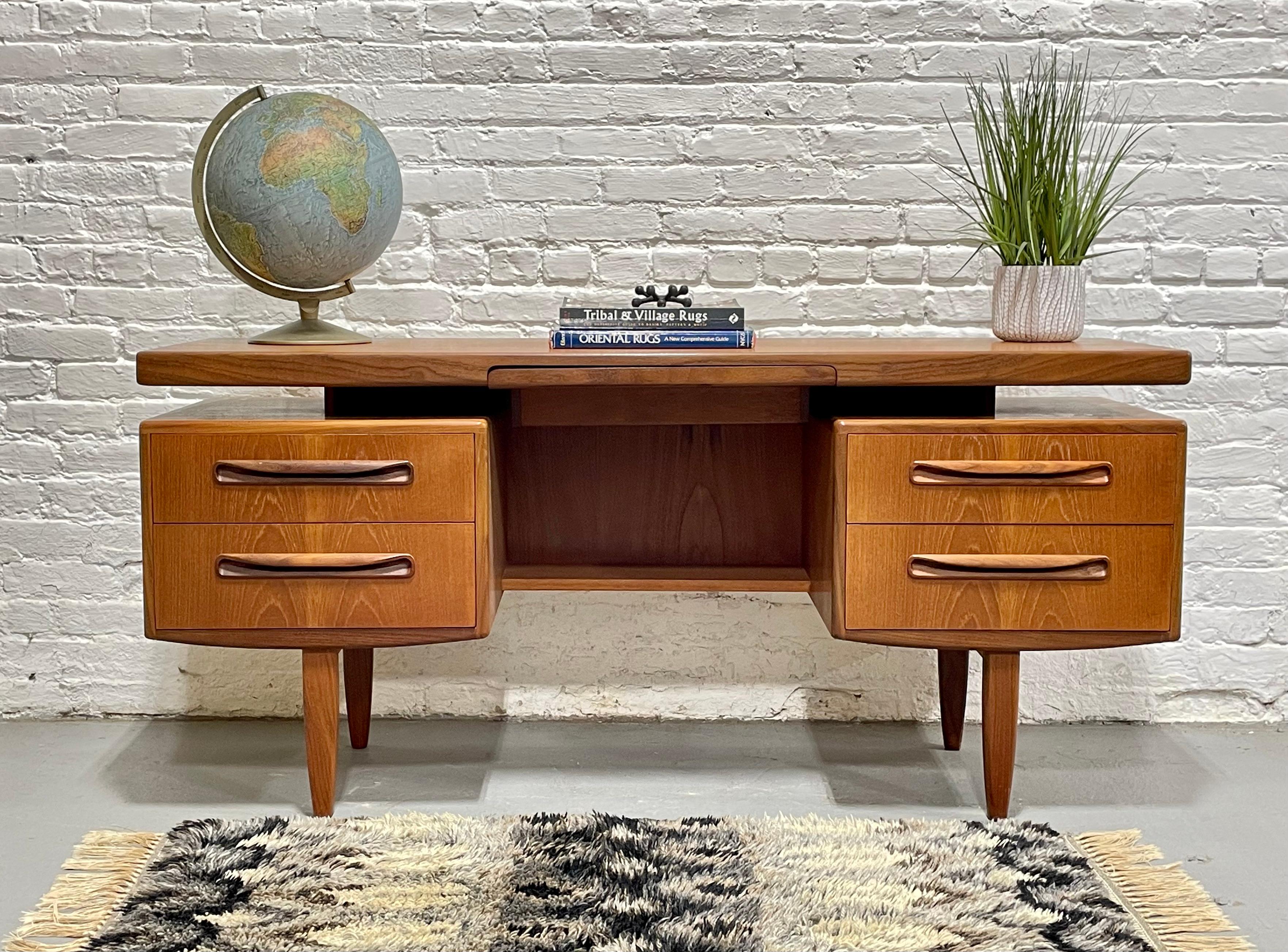 Mid Century Modern Teak Desk, designed by V.B. Wilkins for G-Plan, c. 1960’s. Designed as part of the “Fresco” series, this piece boasts sculpted handpulls, rounded edges and a floating tabletop. Each side boasts two deep and spacious drawers and