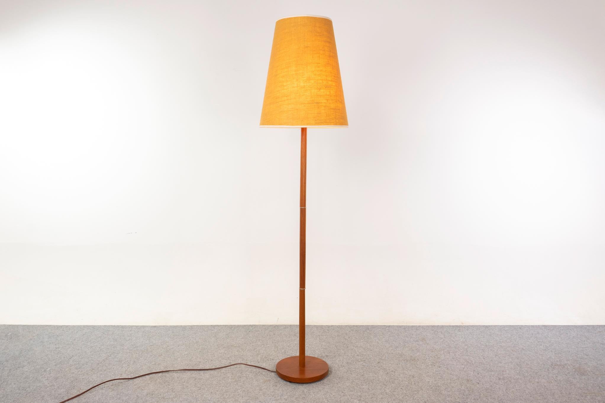 Lampadaire danois en teck, circa 1960. Lignes épurées et élégantes, la prise tri-lumière permet d'obtenir 3 niveaux de luminosité différents. Teinte originale avec une légère usure.