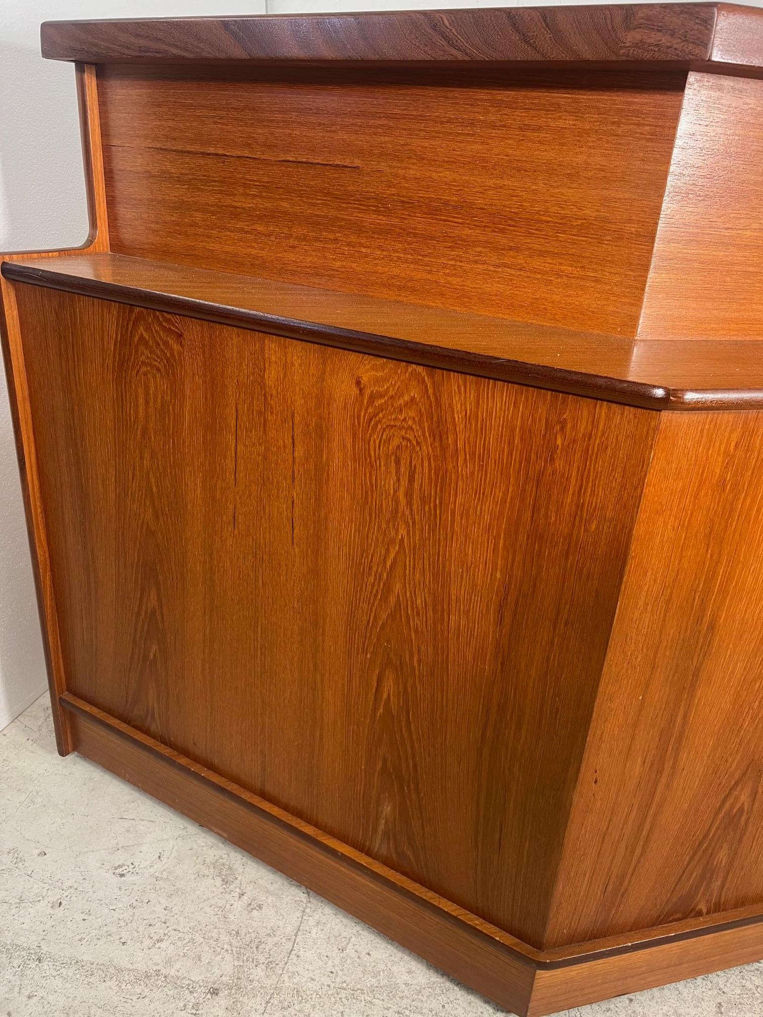 This is an amazing 1970's teak veneer cocktail bar by Turnidge of London. Made in England.

Features side panel that can be attached to the left or right. There are glass doors on the side panel. There are sliding glass doors and two regular doors
