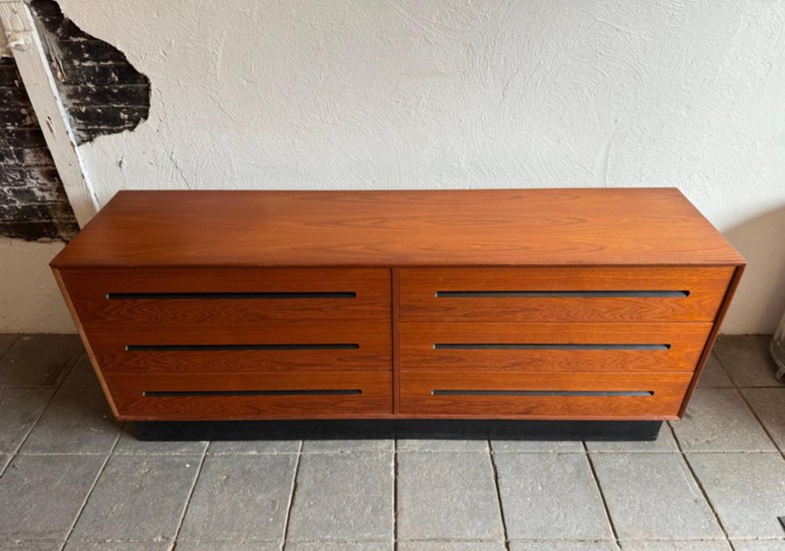 Beautiful Mid Century Modern Teak low long 6 drawer Dresser by Westnofa Made In Norway. Very simple design with inset handles with black lacquer paint. Very stunning curved design and teak wood grain. This dresser sits on a black lacquered plinth