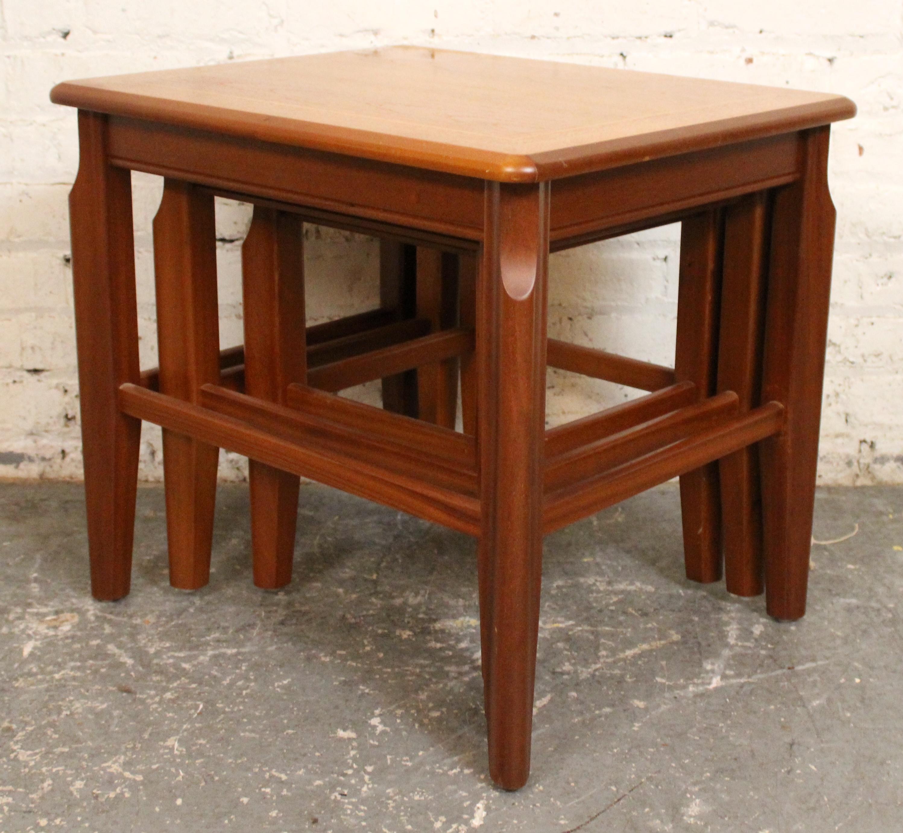 A sleek set of mid-century modern nesting tables crafted in warm, richly grained teak. Featuring clean lines and a minimalist profile, these versatile tables tuck neatly beneath one another, offering flexible functionality and timeless