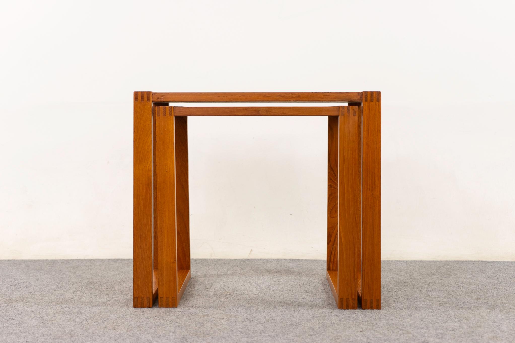 Teak Danish nesting tables, circa 1960s, Golden teak veneer with lovely grain patterns. Eye-catching corner joinery and sleigh leg design. A compact duo!  

An unrestored item with the option to purchase in restored condition for an additional $150