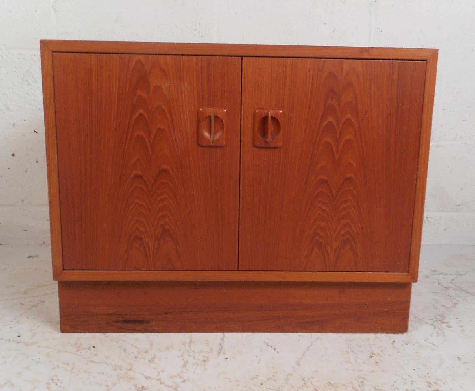 This Mid-Century Modern nightstand features two cabinet doors with carved pulls hiding a large compartment with a shelf. A functional design that works perfectly as an end table or a nightstand for any room in the house. This beautiful teak case