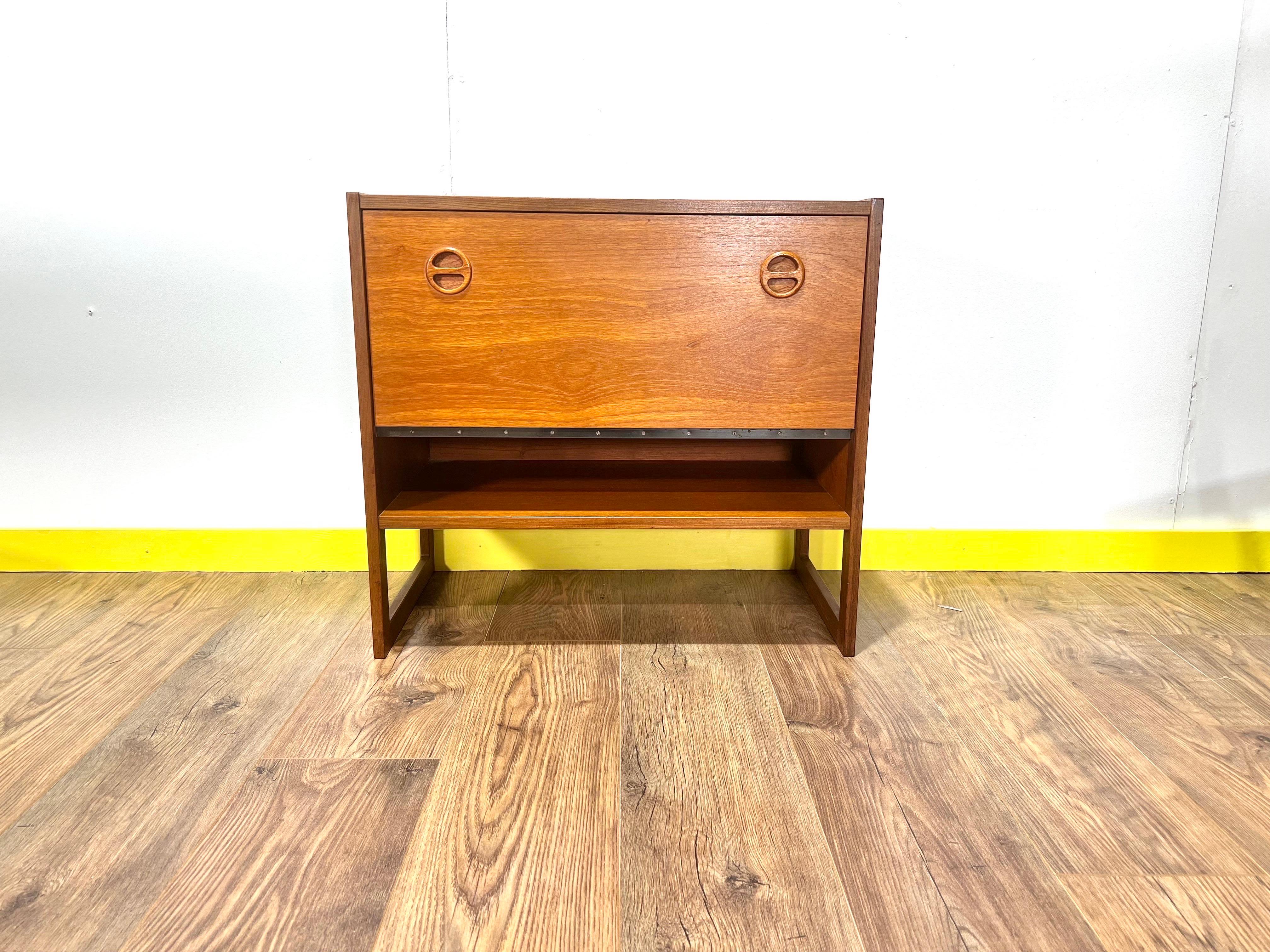 Mid century modern teak record cabinet. This gorgeous little cabinet can be used for a variety of purposes. The pull door with its frog eye handles reveals dividers for records/books and a handy space for storage.

It would look great in any spae