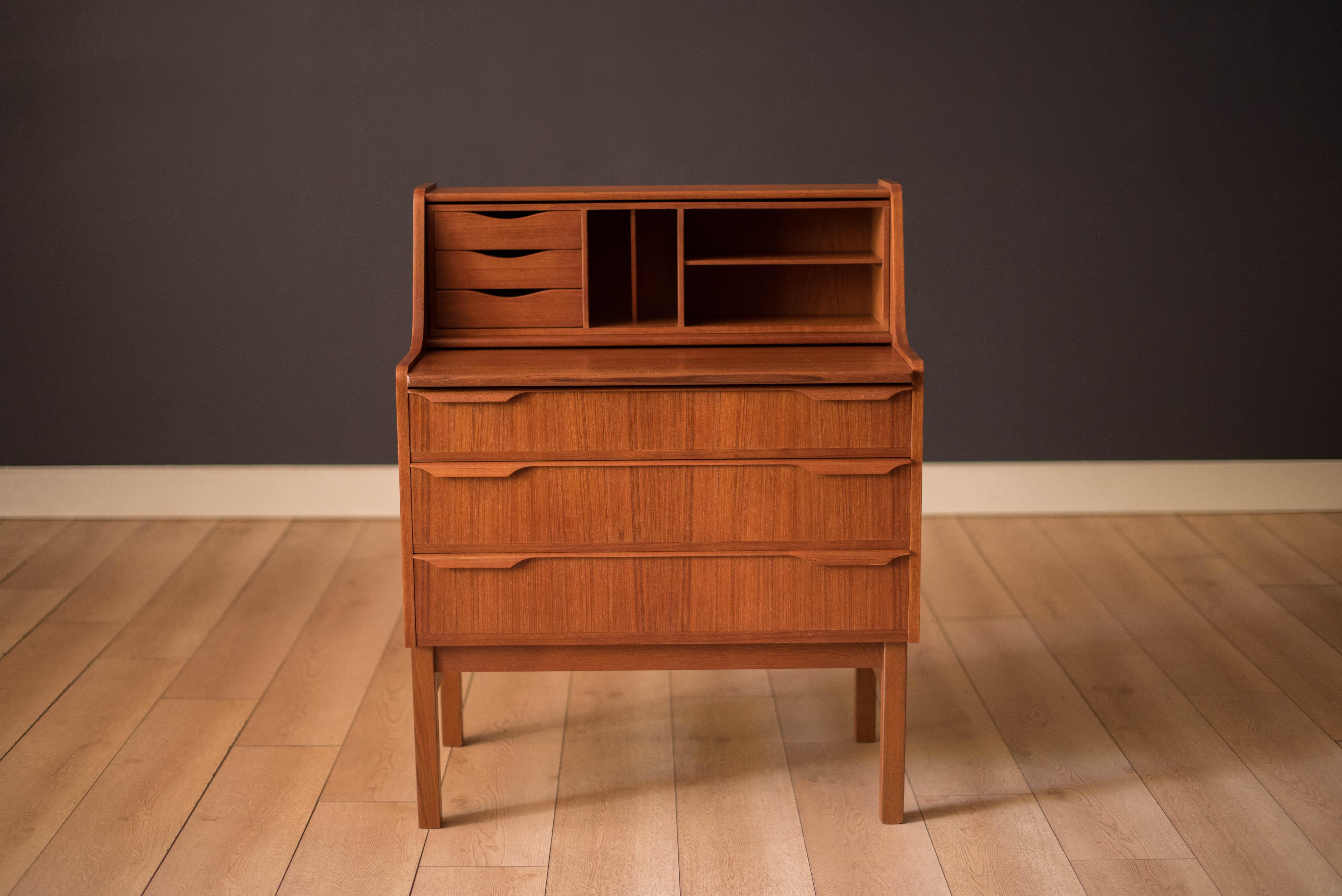 Vintage secretary desk with chest of drawers in teak manufactured by Trekanten, Denmark. Features a hidden mirror vanity slide out desk to maximize space and three dovetailed storage drawers with sculpted pulls. This versatile piece includes a