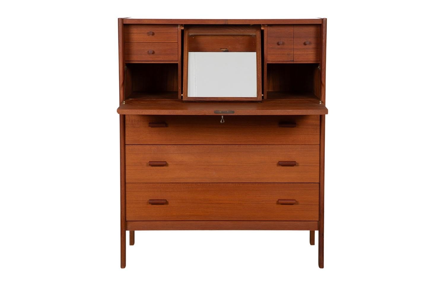An elegant Mid-Century Modern teak secretary desk or vanity with mirror. Featuring beautifully grained teak wood case and frame. The upper drop down cabinet features a single push drop down lock door, with a key that opens to reveal a hidden mirror,