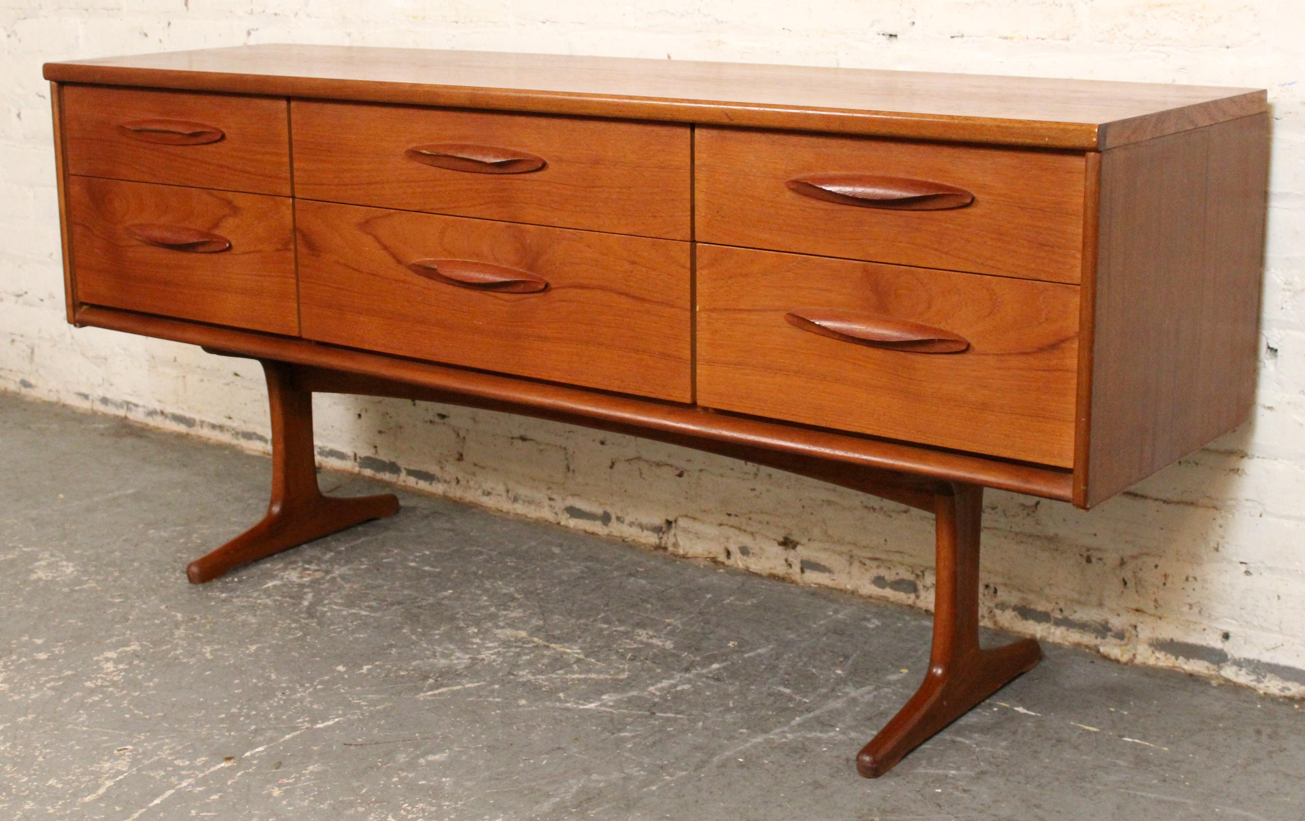 Crafted by British maker Austinsuite, this teak sideboard beautifully balances refined Mid-Century aesthetics with practical storage. It features a clean, rectangular teak case supported on sculpted legs, offering a spacious interior concealed