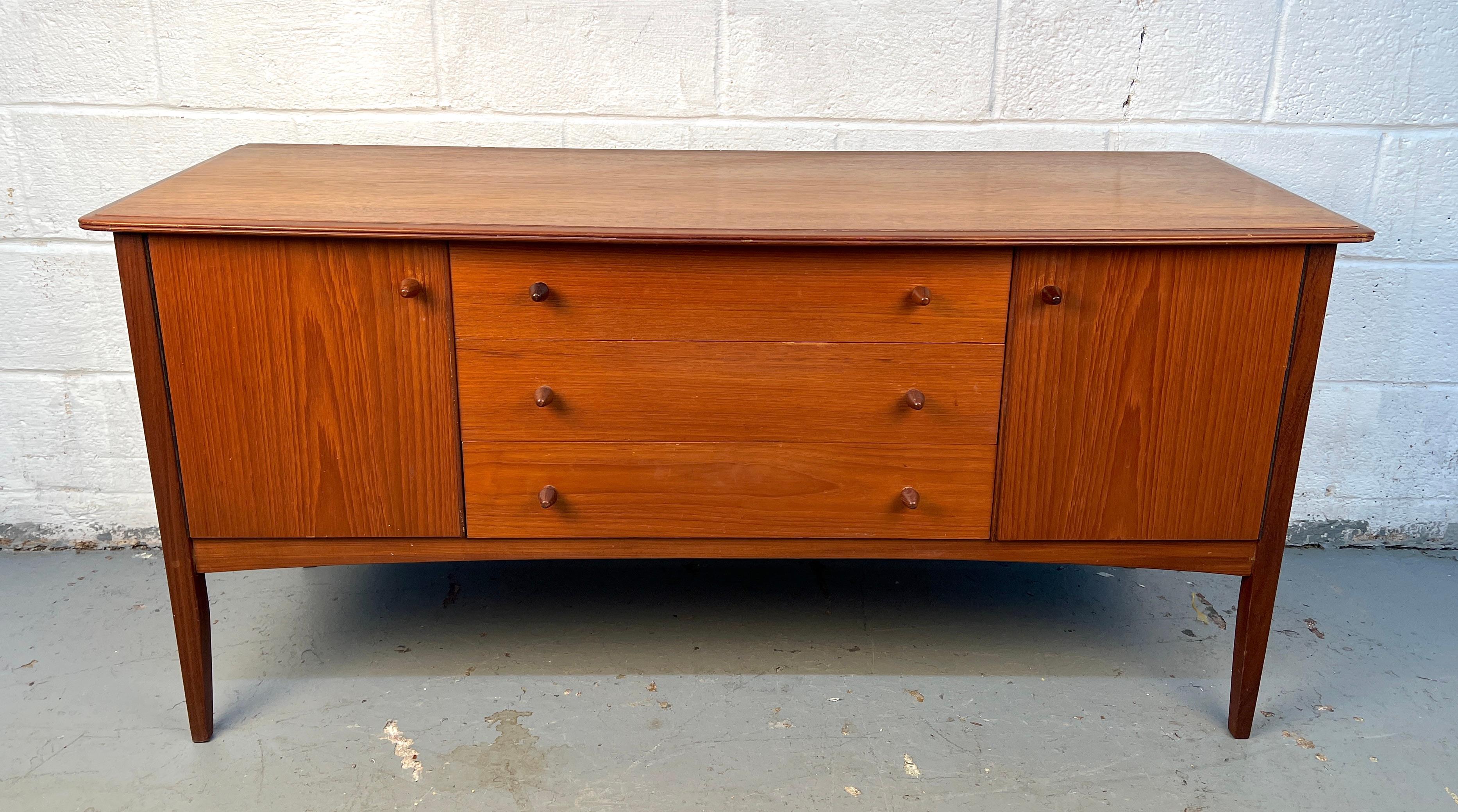 Eleganza della credenza moderna di metà secolo di Robson & Sons, realizzata in teak a grana fine. Prodotto in Inghilterra negli anni '60, questo mobile presenta linee pulite e un ampio spazio di archiviazione, combinando un design senza tempo con la