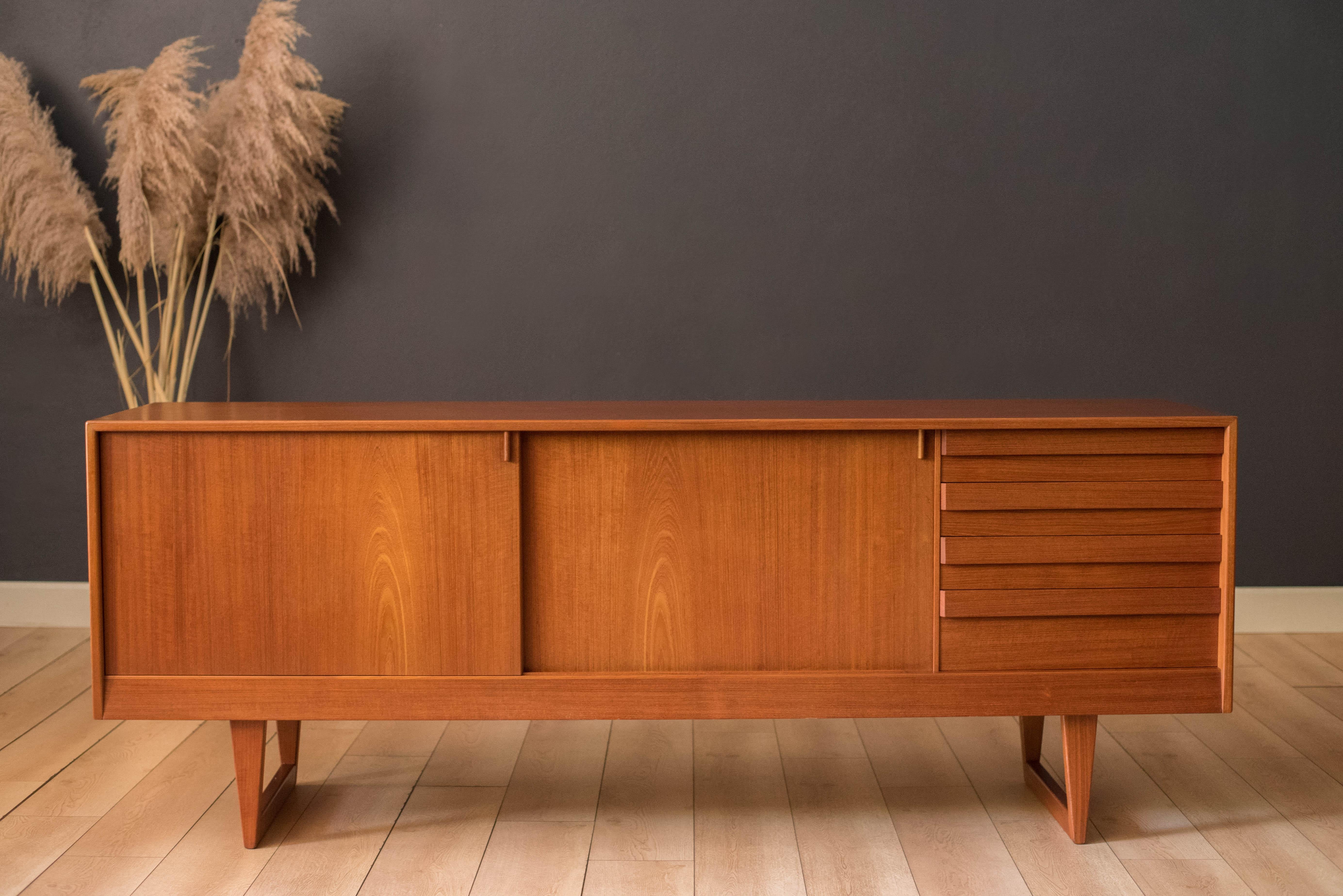 Vintage Danish modern sideboard credenza in teak designed by Kurt Ostervig for KP Mobler, made in Denmark, circa 1960s. This piece maximizes storage space including four organizing dovetail drawers and sliding doors that reveal two open cabinets