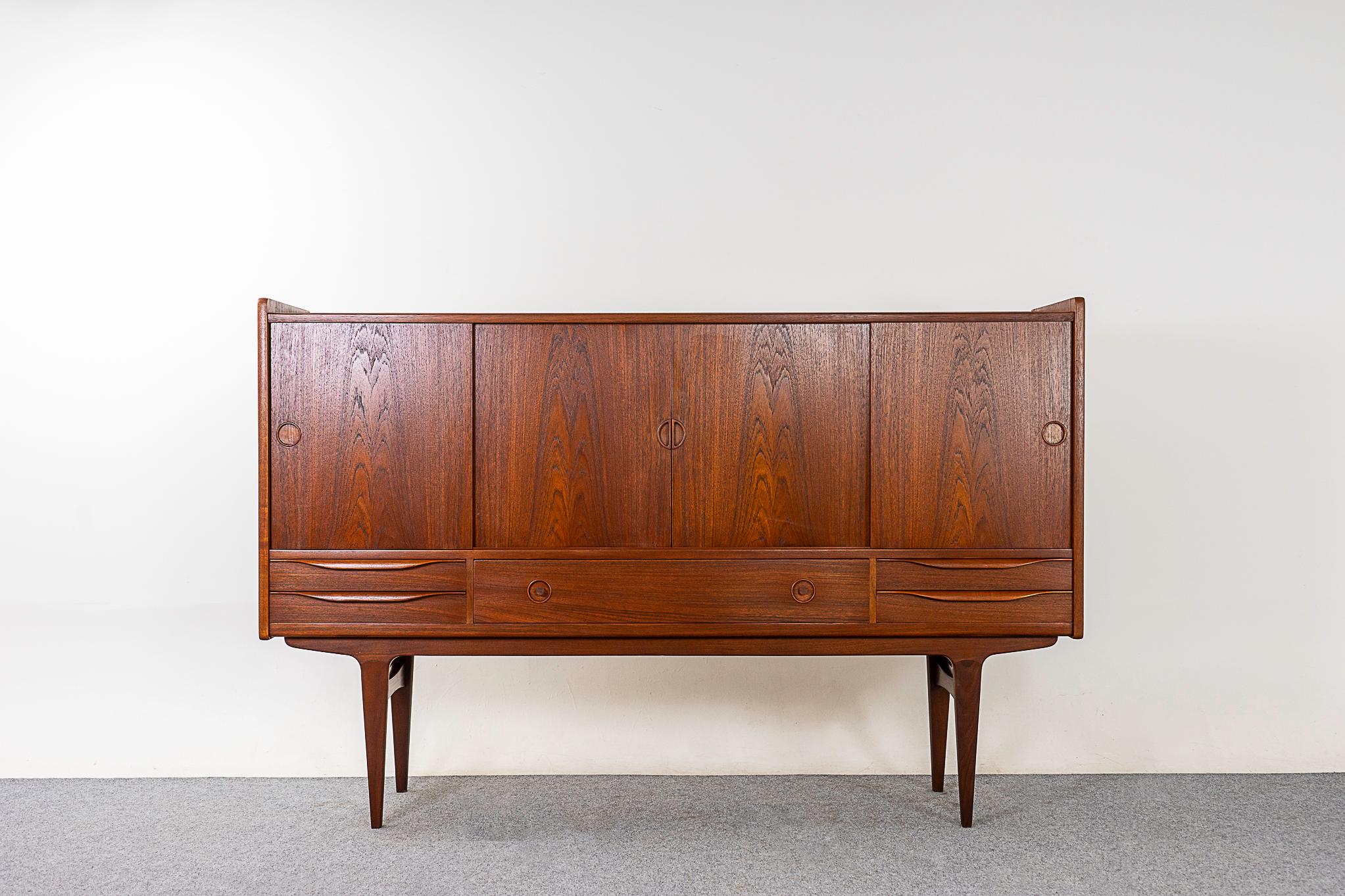 Teak Danish tall sideboard, circa 1960's. A combination of sliding doors and exterior drawers, ample storage for a variety of uses! Interior compartments showcase adjustable shelving and felt lined sleek dovetailed flatware drawers. Clean, simple