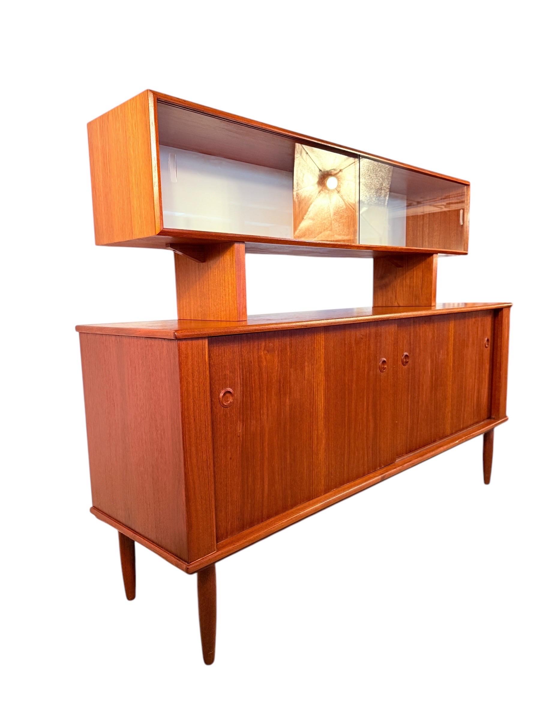 A striking mid-century modern teak sideboard and hutch set by R. Huber, crafted in the 1960s. This two-piece unit showcases clean Scandinavian-inspired lines, tapered legs, and minimalist circular recessed pulls, all wrapped in rich, warm teak.

The