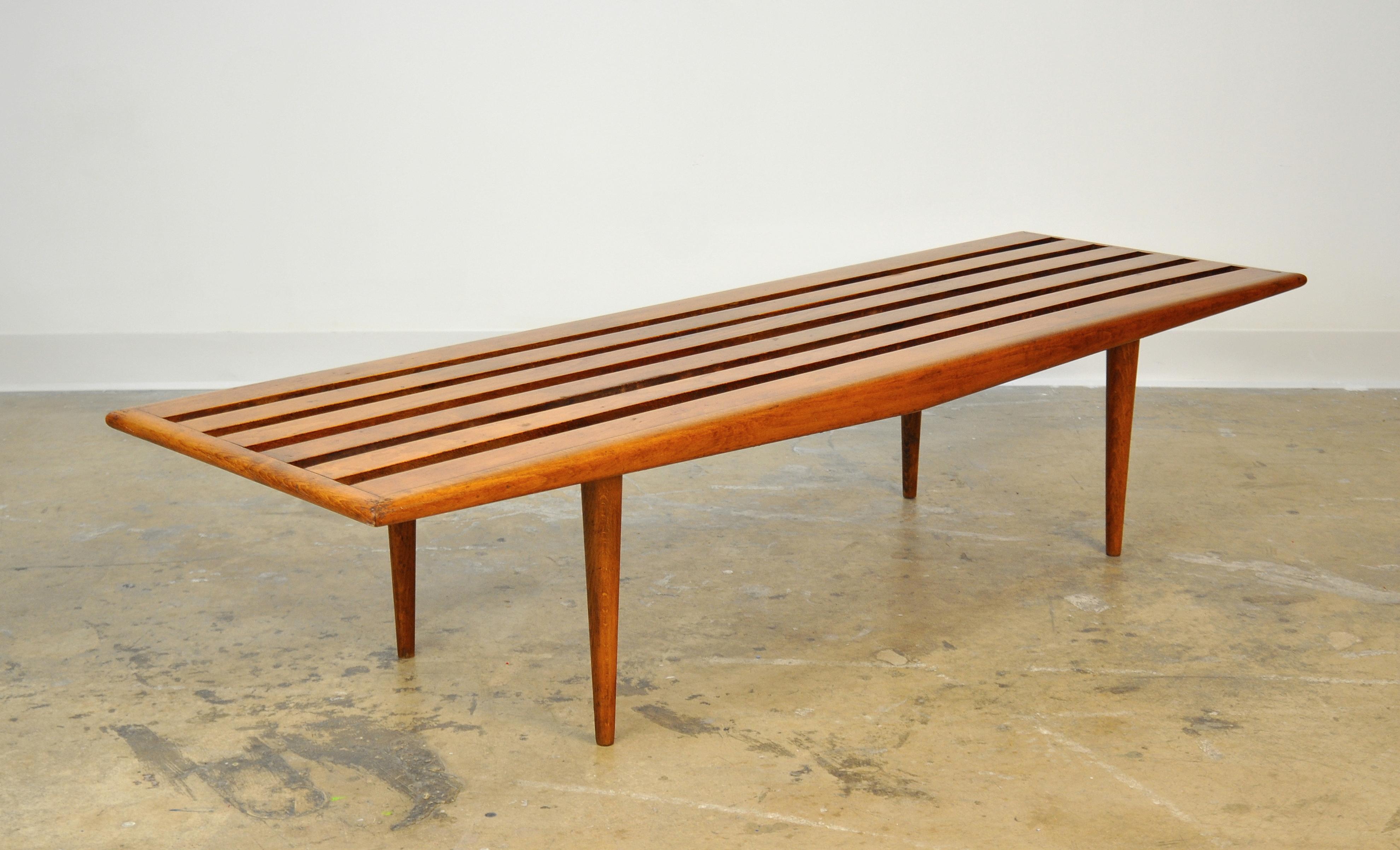 A midcentury long, slatted wood coffee table, dating from the 1960s. The vintage bench features long and slender tapered legs. It can be used virtually anywhere: As a cocktail or sofa table, at the foot of a bed, under a window, in an entrance