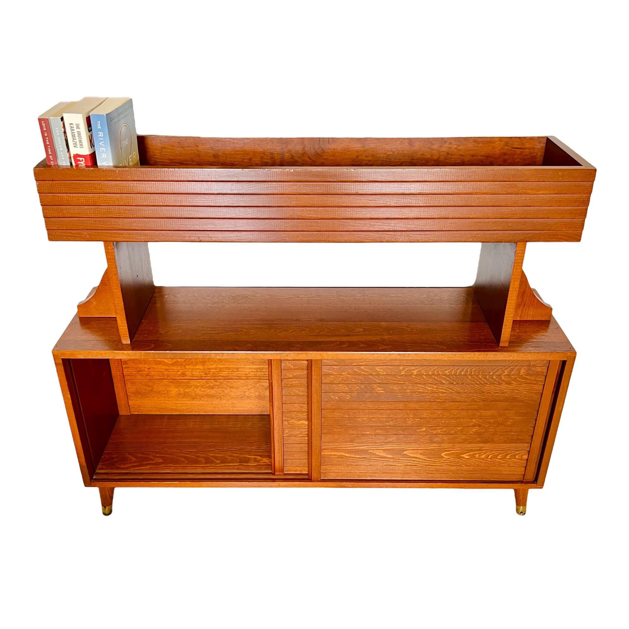 A vintage Mid-Century Modern teak credenza with upper display shelf. This unique compact piece is finished on both sides and features lower storage with four removable horizontally sliding tambour detail doors and an upper shelf with tamboured