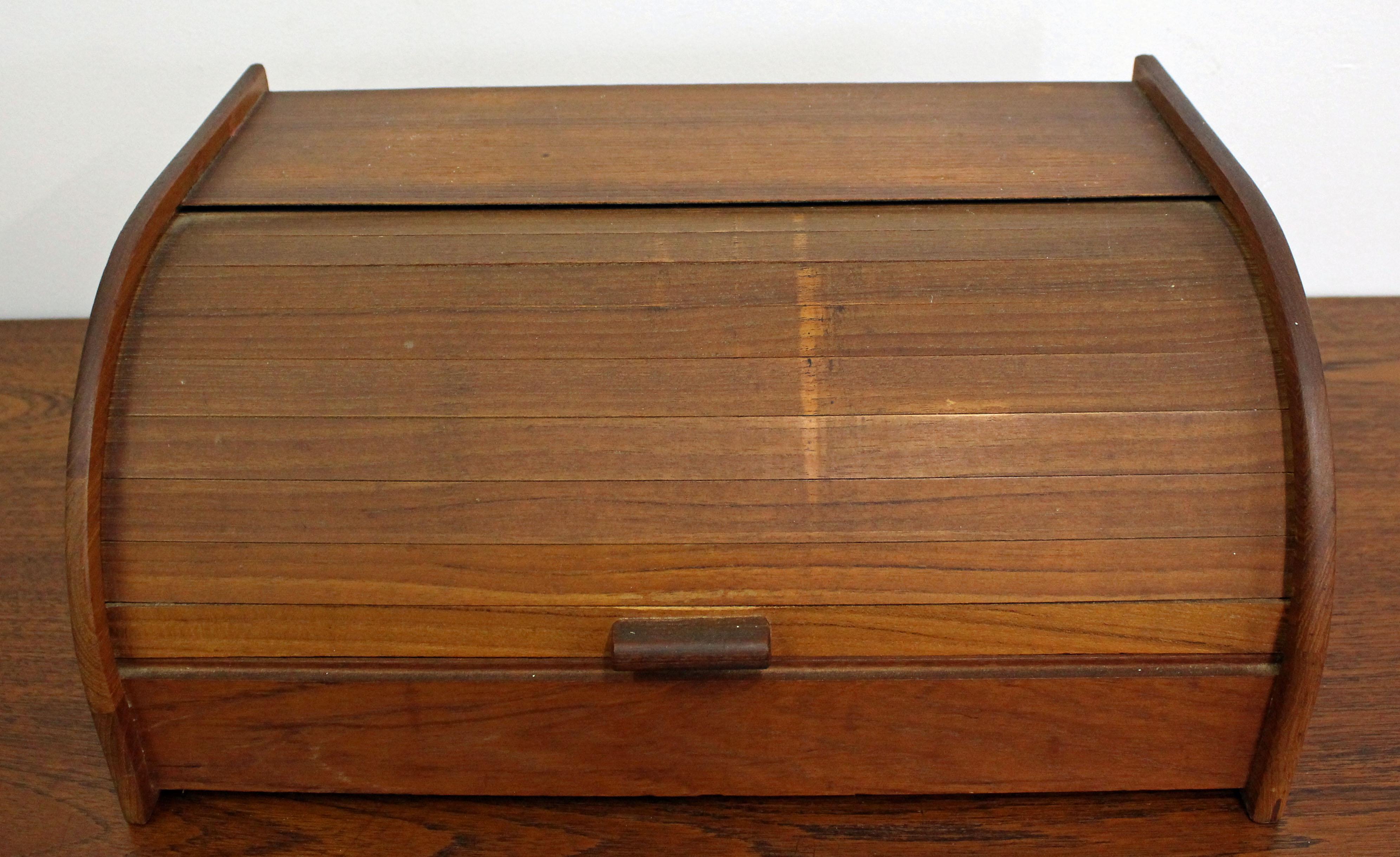 Offered is a versatile midcentury storage box. This piece is made of teak and has a tambour roll-top door. Can be used for extra storage, as a breadbox, etc. It is in good condition, shows some age wear (surface wear, some discoloration - see