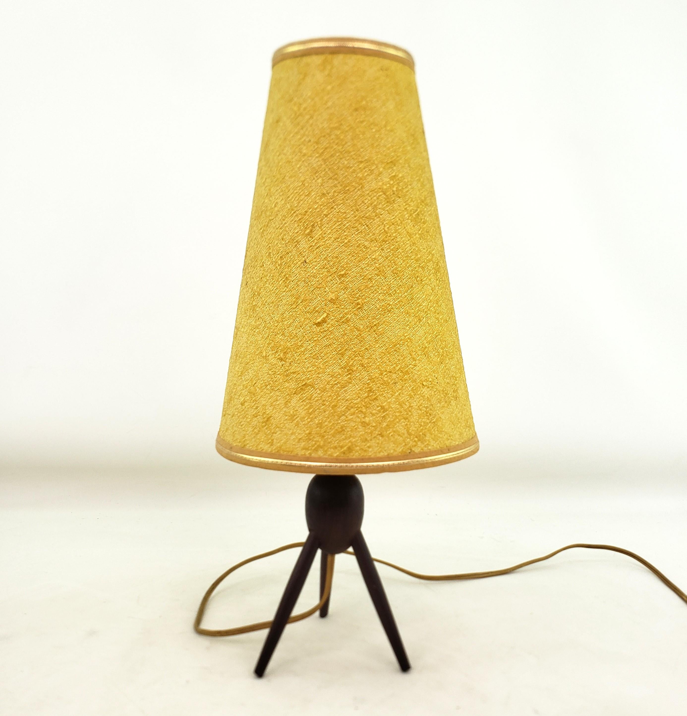 This small accent table lamp is unsigned, but presumed to originate from Denmark and date to approximately 1960 and done in the period Mid-Century Modern style. The lamp base is composed of solid teak wood with a  ball center and three spayed teak