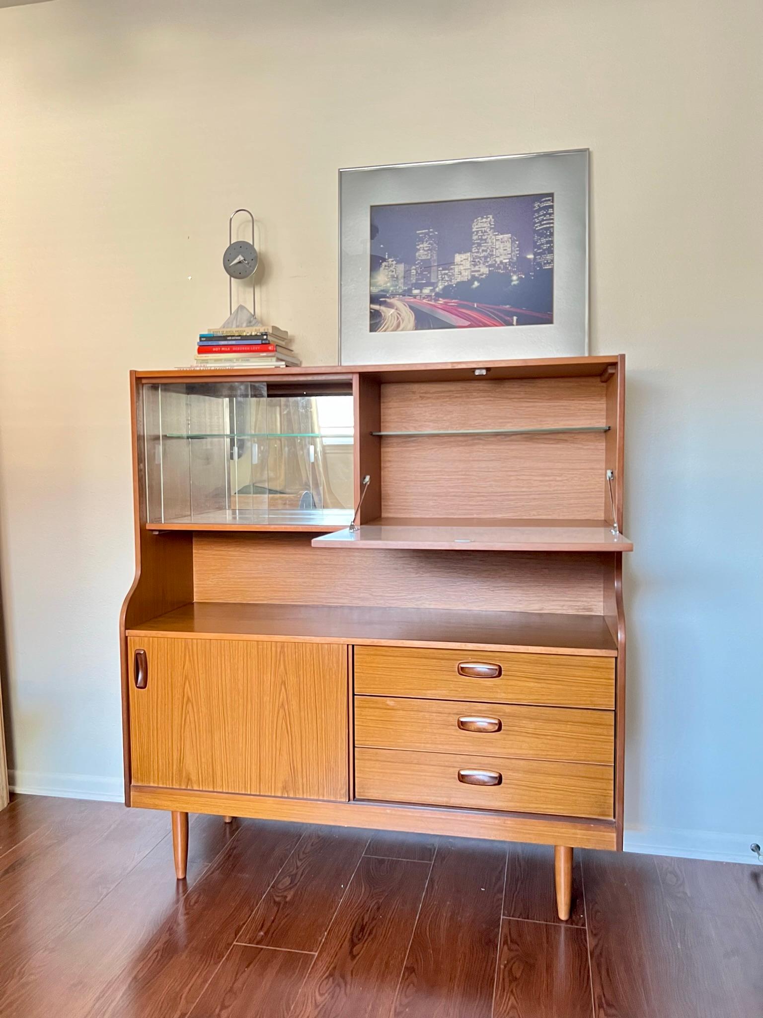 Beautiful mid century modern teak veneer hutch by Schreiber. This beautiful piece of hand made furniture offers plenty of storage in addition to being such an incredible statement piece. Both shelves are removable but not height adjustable in the