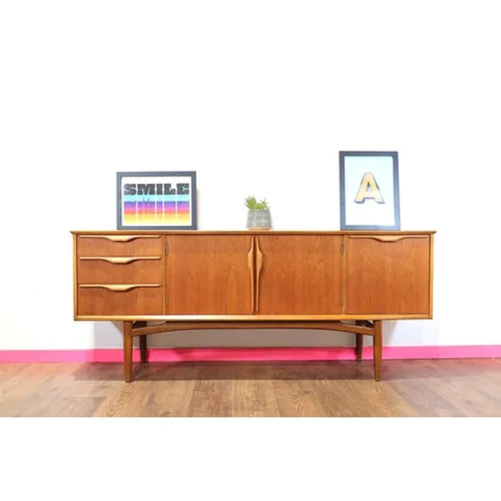 This Mid Century Modern Teak Vintage Danish Style Sideboard Credenza by Jentique is a wonderful example of mid century style, capturing the sleek and sophisticated design aesthetic of the 60s. Crafted from high-quality teak wood, this credenza