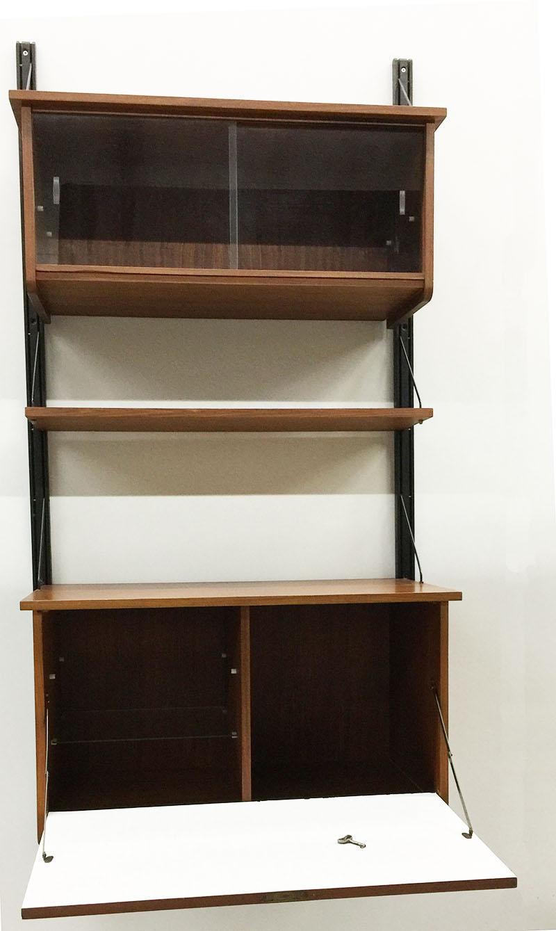 Mid-Century Modern teak wall unit with dry bar.

A teak compartment with sliding glass doors
A teak shelve
And a teak dry bar with flip door compartment, including key

The measurements are:

In total height is 175 cm
The compartment with