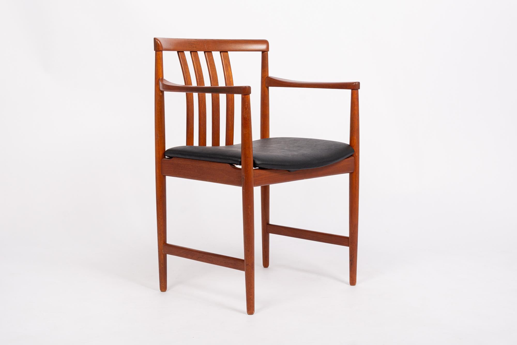 This vintage mid century modern arm chair was made in Norway by Westnofa circa 1968. The elegant Scandinavian design features clean, minimalist lines and gentle curves. The chair is well-constructed with a solid teak wood frame and simple black