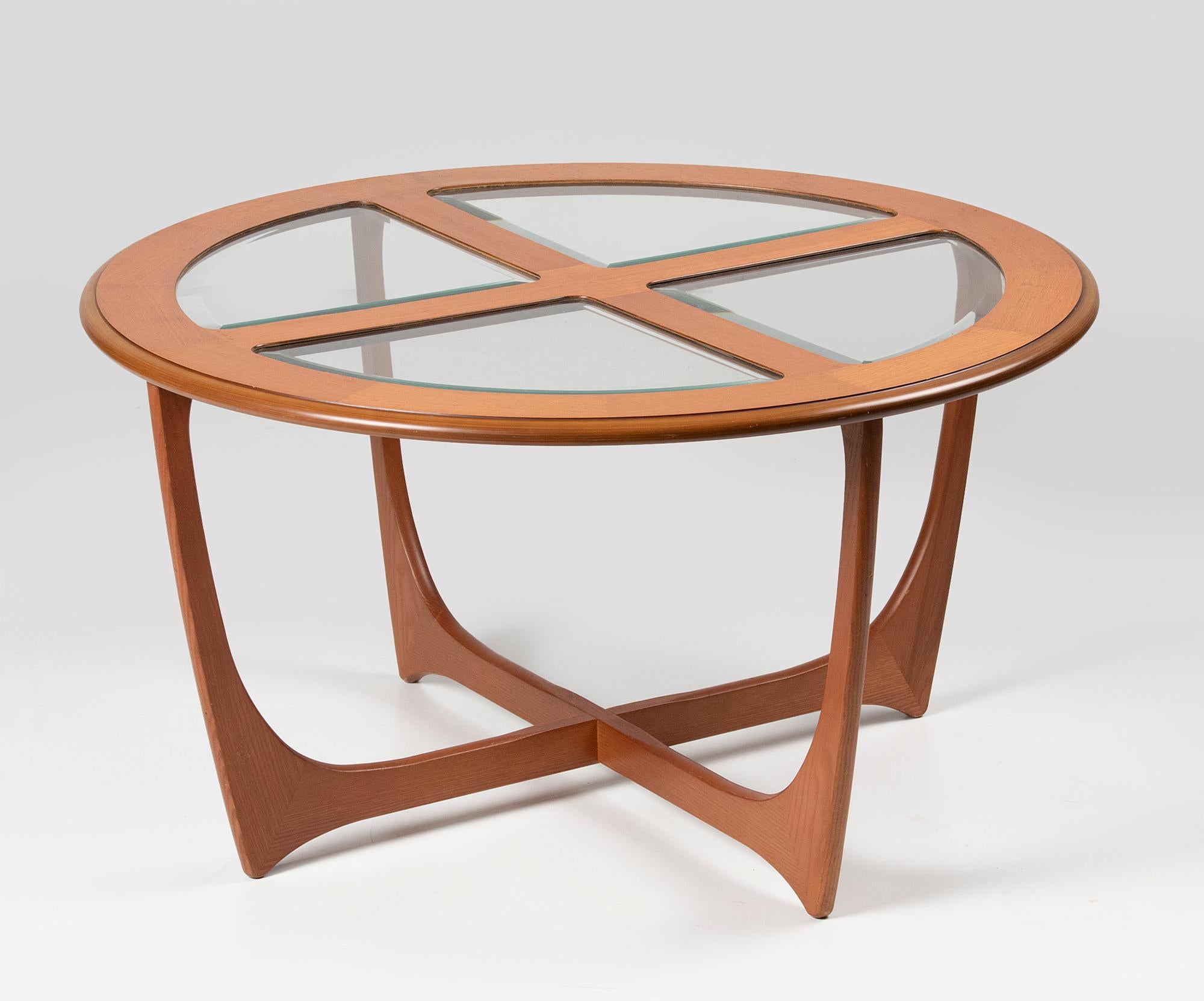 An iconic round G-Plan coffee table. Attributed to Victor Wilkins. The top is made of veneered teak wood. The base is made of solid Afromosia wood (African teak wood). The top is divided into four glass beveled panels.