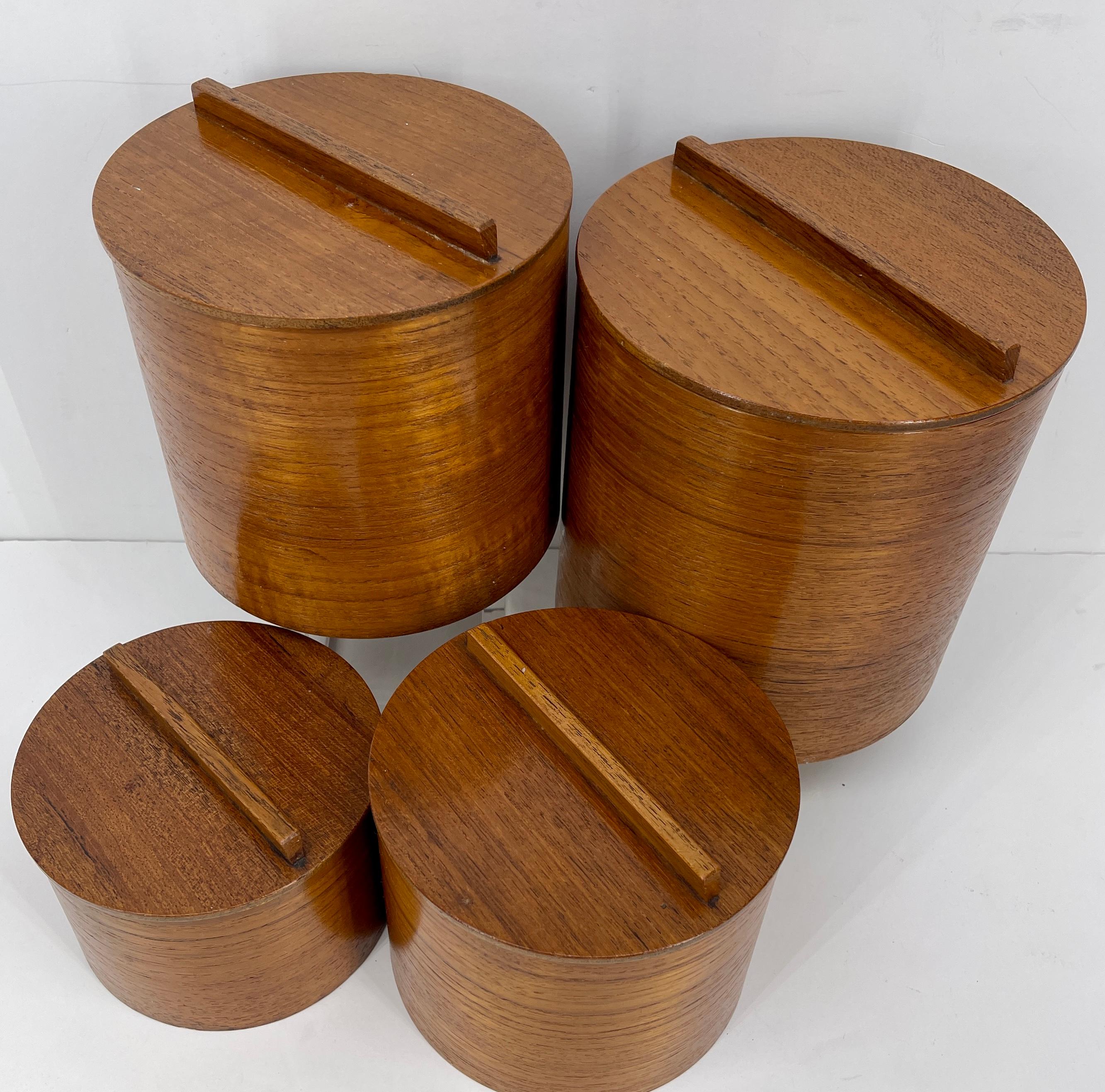 Set of four Japanese Mid-Century Modern teak kitchen canister set. 
This sleek teak boxes set is perfect for any kitchen. The largest canister has wooden scoop for flour or sugar. The graduated set is perfect for flour, sugar, coffee, and salt.