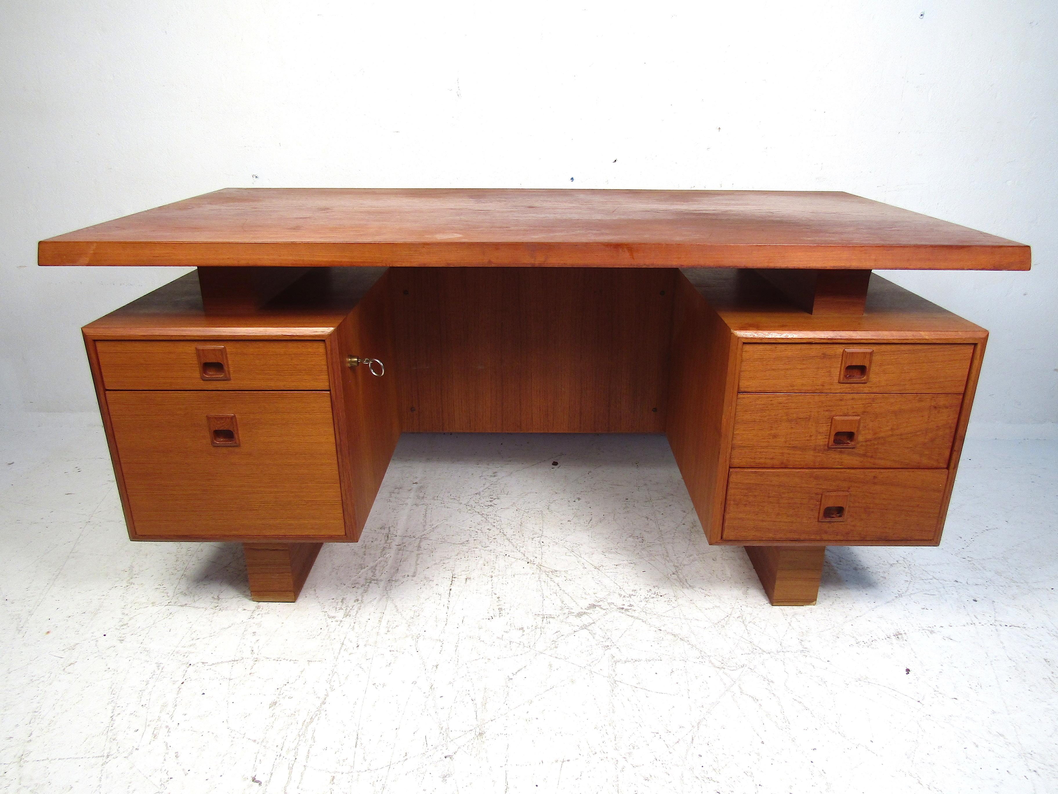 Stylish Mid-Century Modern teak writing desk. Interesting design with a floating desktop, and drawer cases on either end with recessed drawer pulls. Please confirm item location with dealer (NJ or NY).