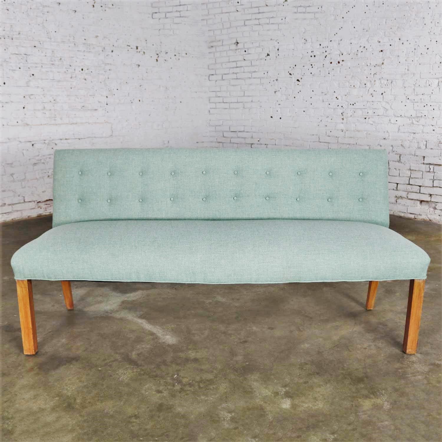 Handsome Mid-Century Modern armless bench with a back and button details done in the style of Tommi Parzinger. It is in wonderful vintage condition and recently recovered in new yet vintage fabric. The legs have been touched up but not refinished as