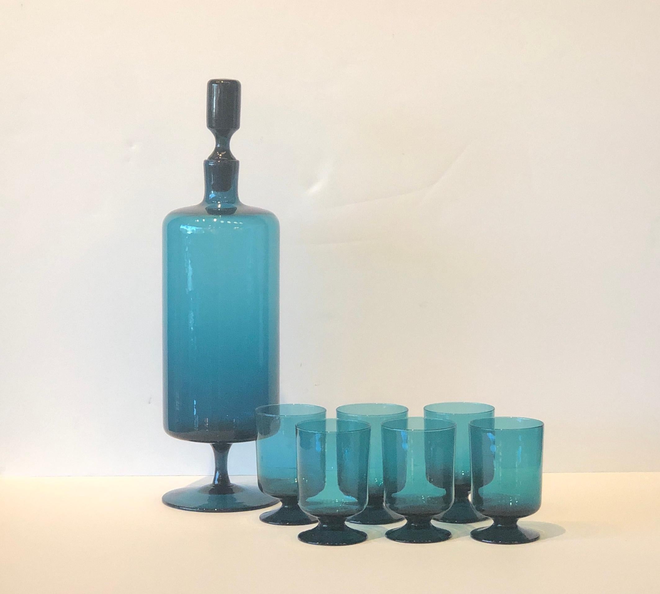 Offered is a beautiful Mid-Century Modern translucent teal blue blown set of six petite stem glasses with a matching tall slender blown glass decanter with a lovely glass stopper. This is truly elegant barware that is both functional and decorative.