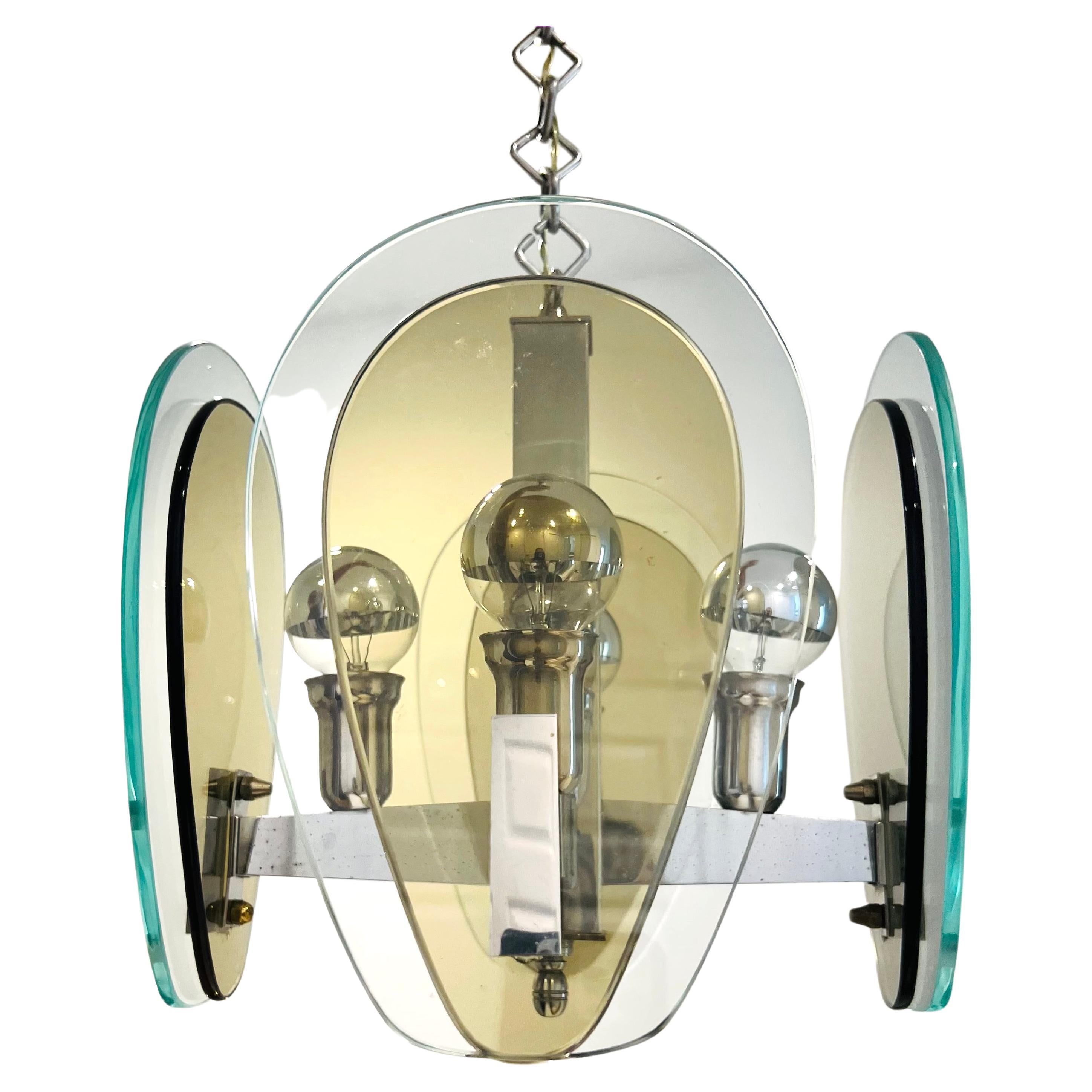 Lampe pendante architecturale italienne à quatre bras, de style moderne du milieu du siècle. Le lustre a une structure chromée équipée de deux abat-jour en verre en forme de goutte d'eau dans des teintes de gris fumé et de vert clair. Il possède une