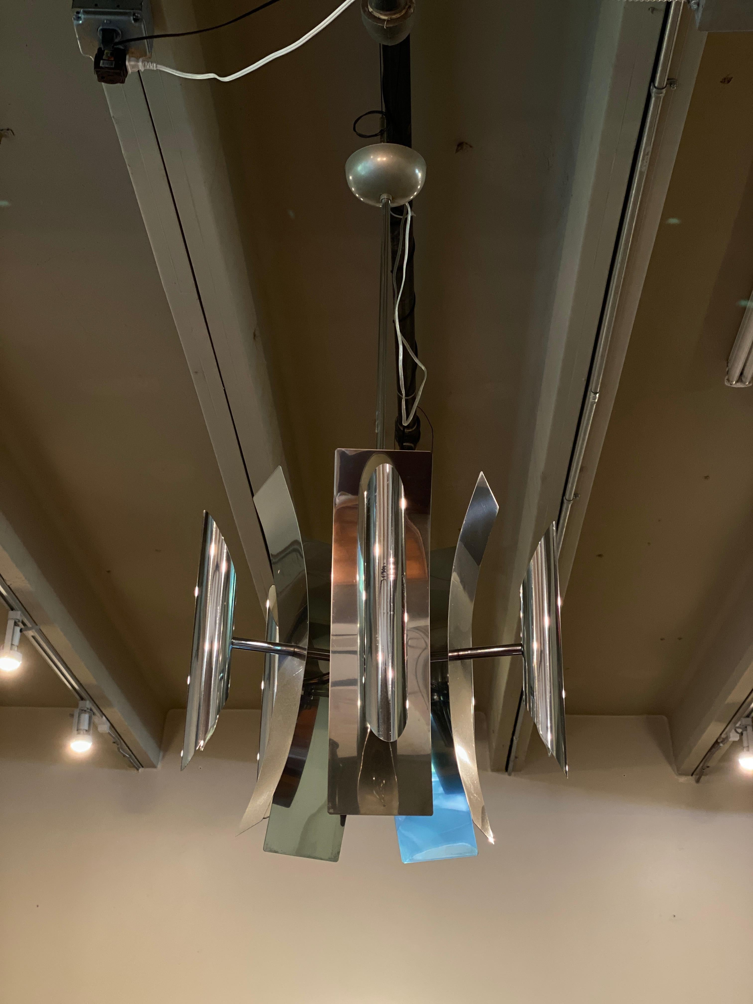 Sculptural hanging chandelier with five stainless or aluminum cylinders, each with upper and lower sockets, backed by curved metal panels. Polished finish is similar to chrome. In the manner of Max Sauze's Cassiope chandeliers. Newly polished and