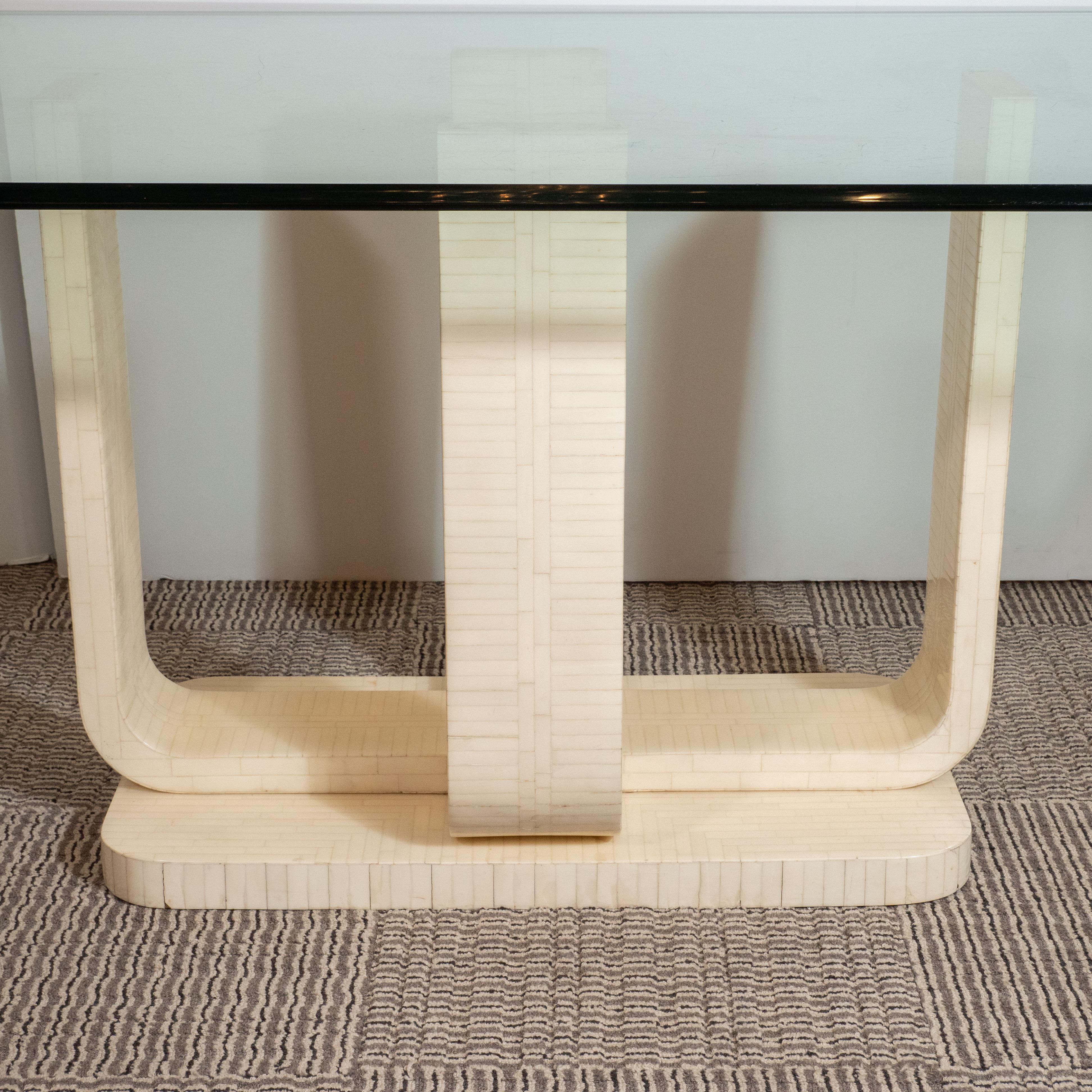 This refined dining table was realized by the esteemed maker, Maitland-Smith, in the United States, circa 1980. Inspired by classic Art Deco design, it features two U-form supports that cross at right angles at their nadir. These supports sit atop a