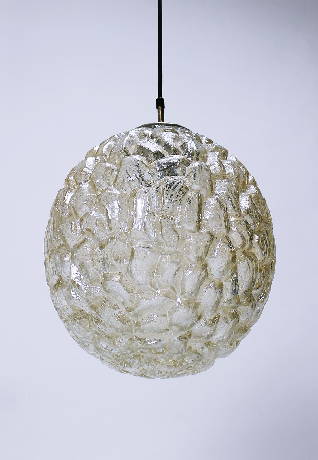 A beautiful and large oval shaped pendant light fixture by Glashütte Limburg, circa 1970s. Featuring a wonderful textured amber colored toned glass shade resembling ice crystals, this midcentury vintage lamp illuminates beautifully, casting a golden